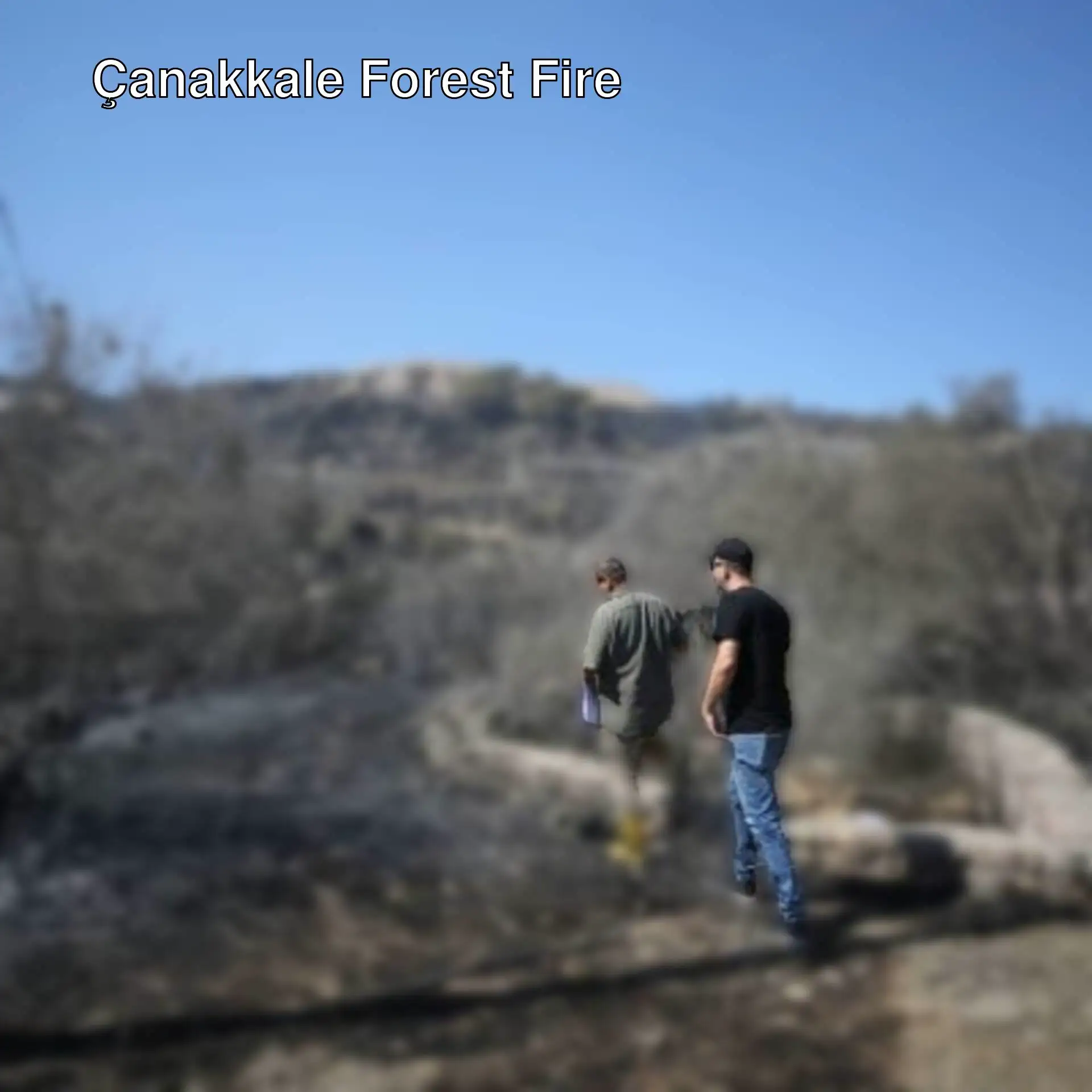 A couple of men standing near a burned area. A couple of men standing near a burned area.