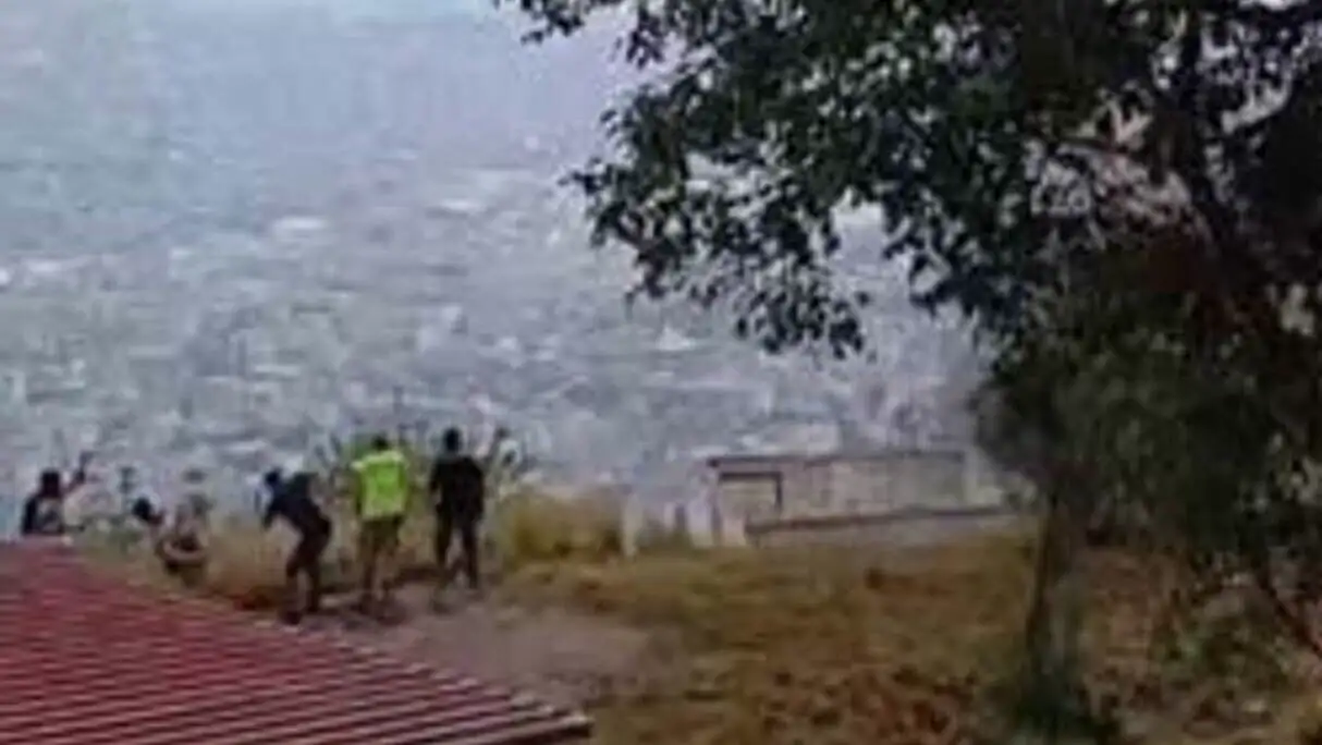 Bir grup insan, bir tepe üzerinde durarak bir şehri izliyor.