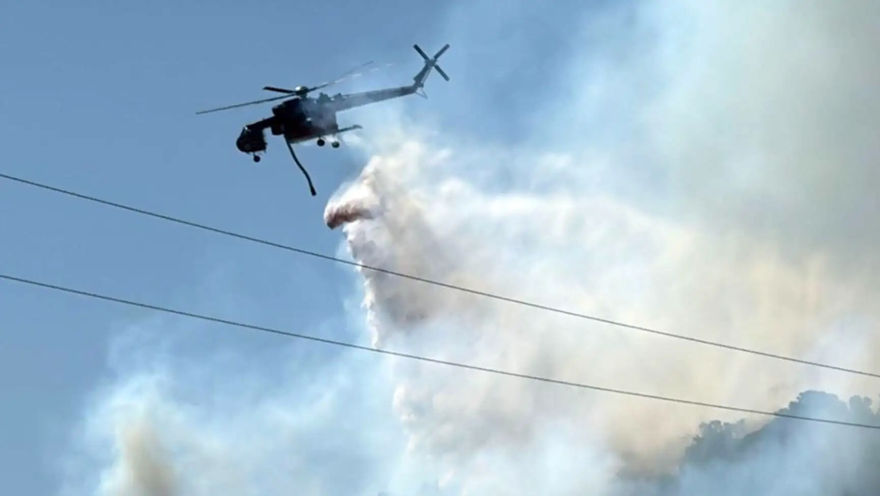Alevlerin üzerinde bir helikopter uçuyor. Alevlerin üzerinde bir helikopter uçuyor.