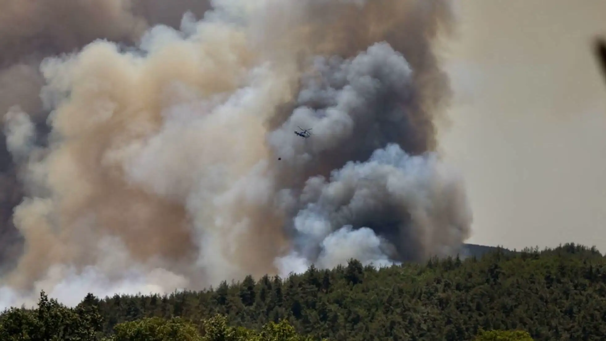 A helicopter flying over a forest fire. A helicopter flying over a forest fire.