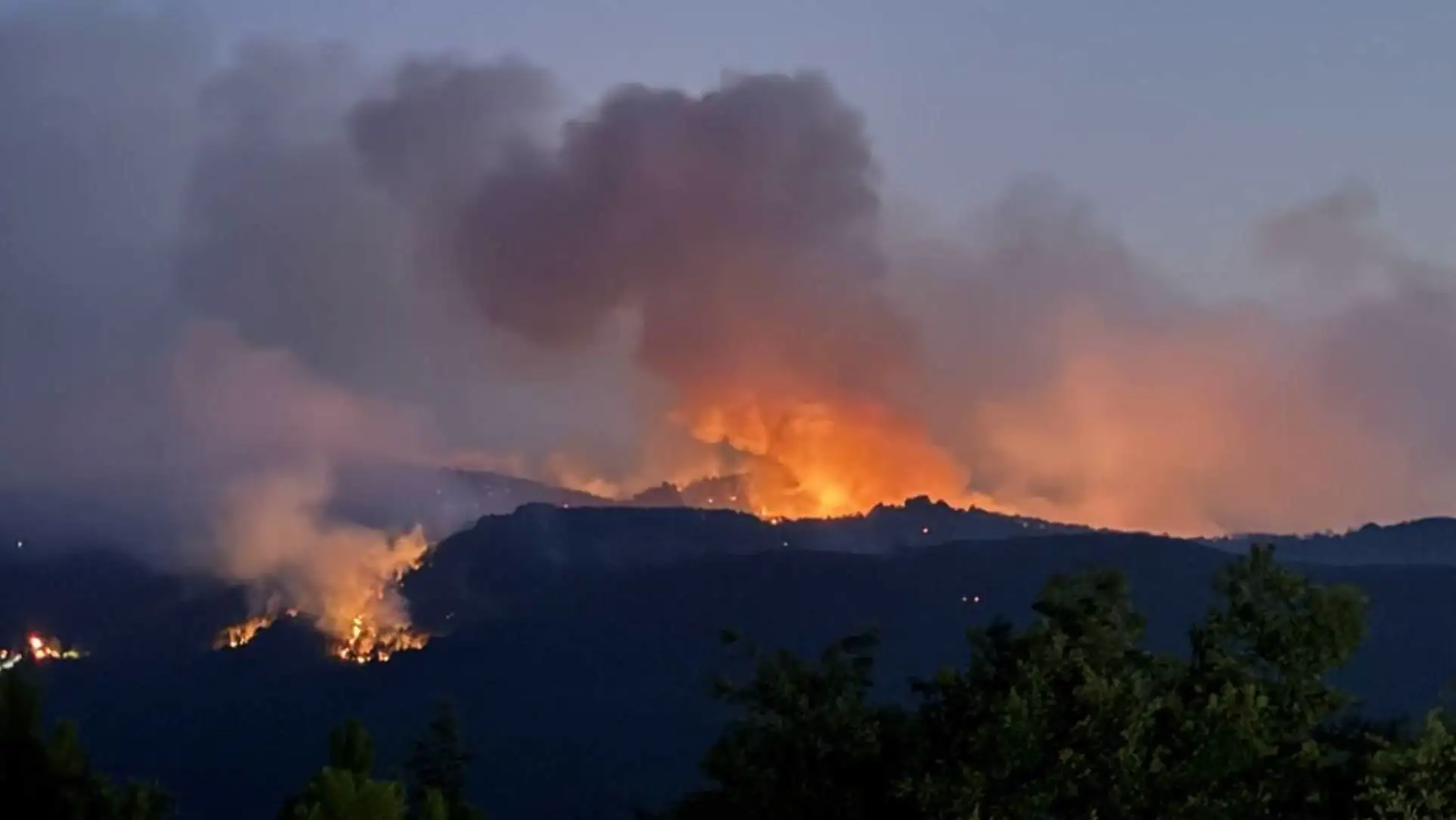 A building on fire in a forest.