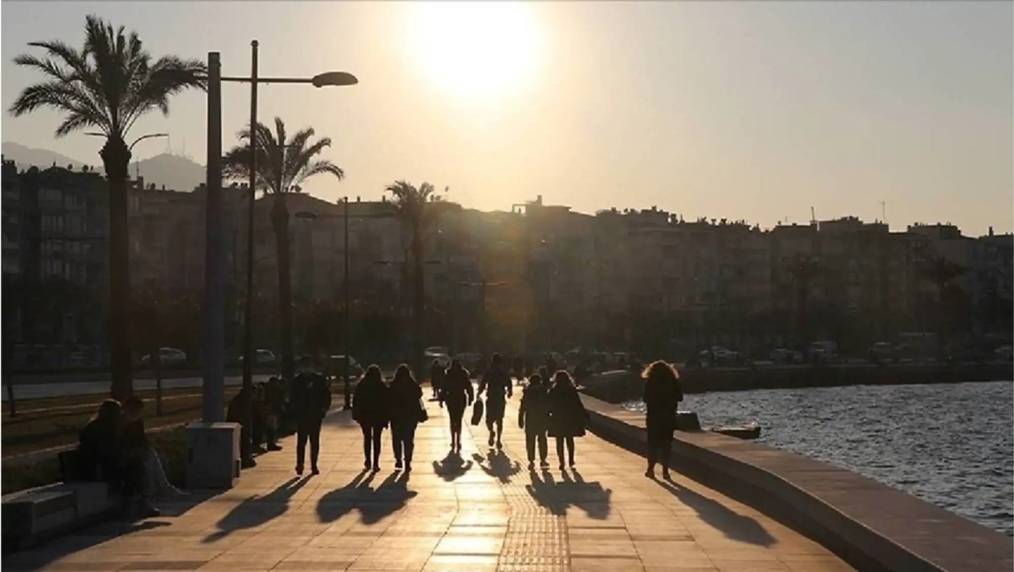 A group of people walking on a sidewalk under the hot weather.
