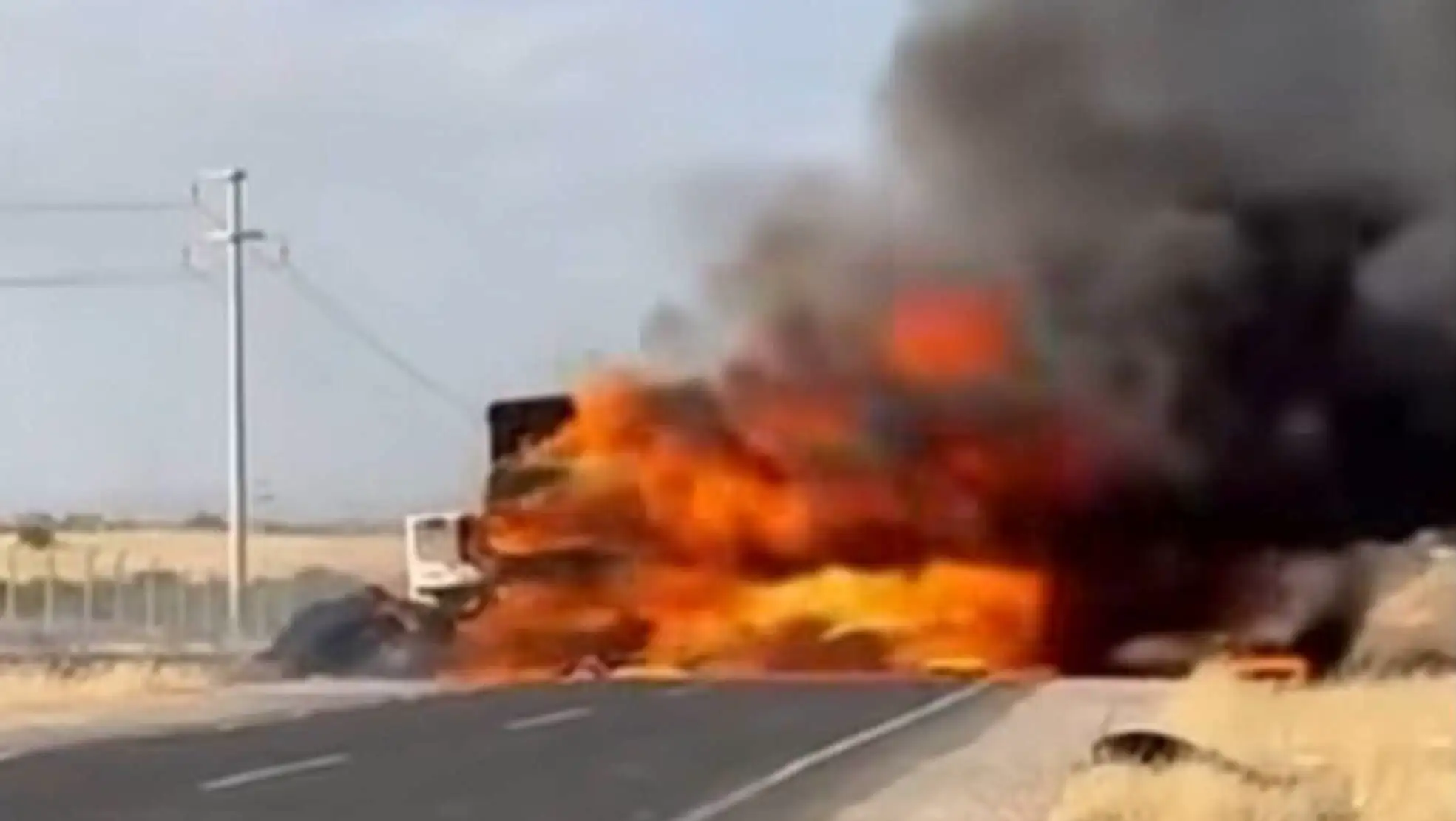 A truck on fire on the road.