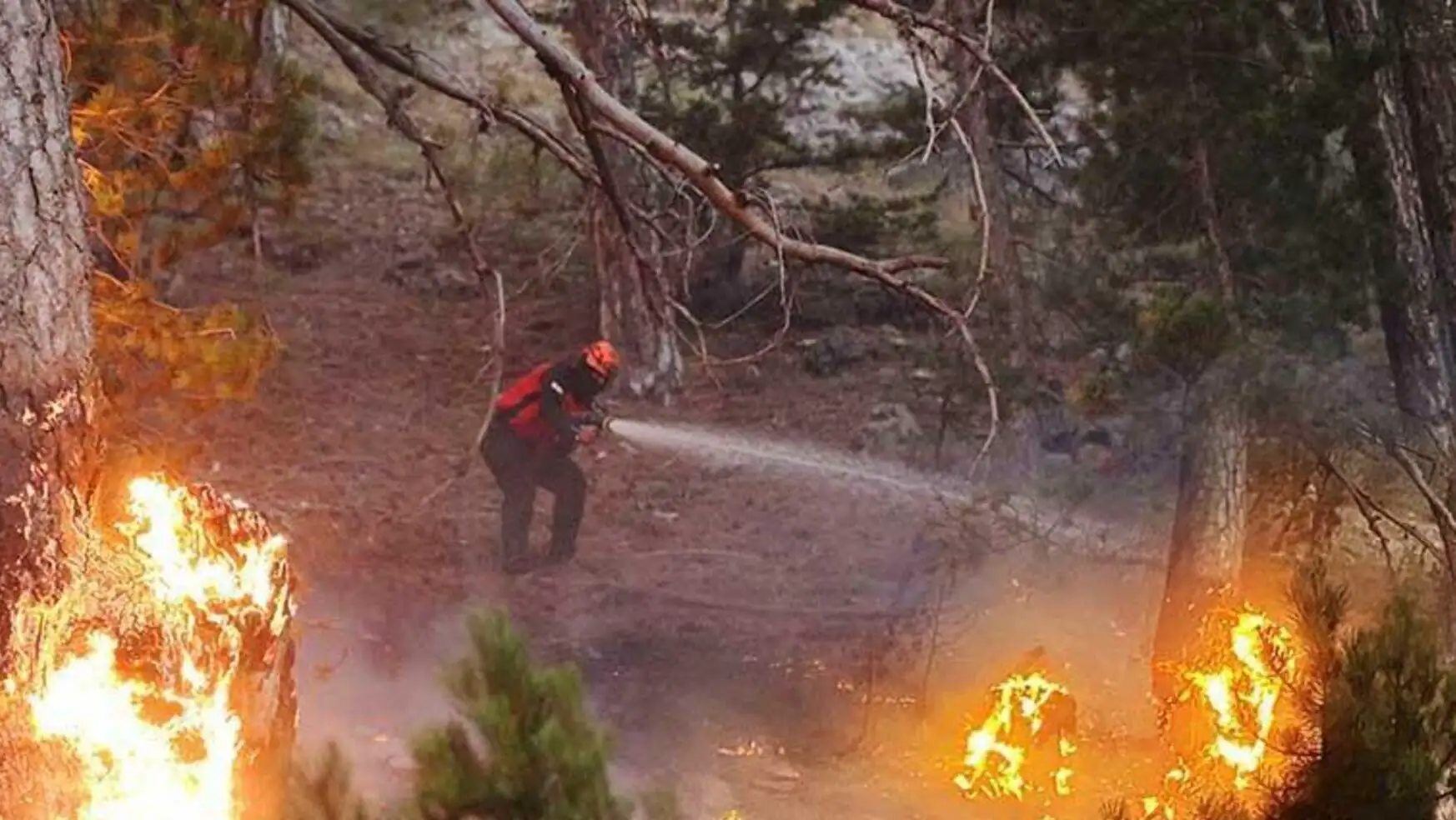 A man spraying water on a fire A man spraying water on a fire