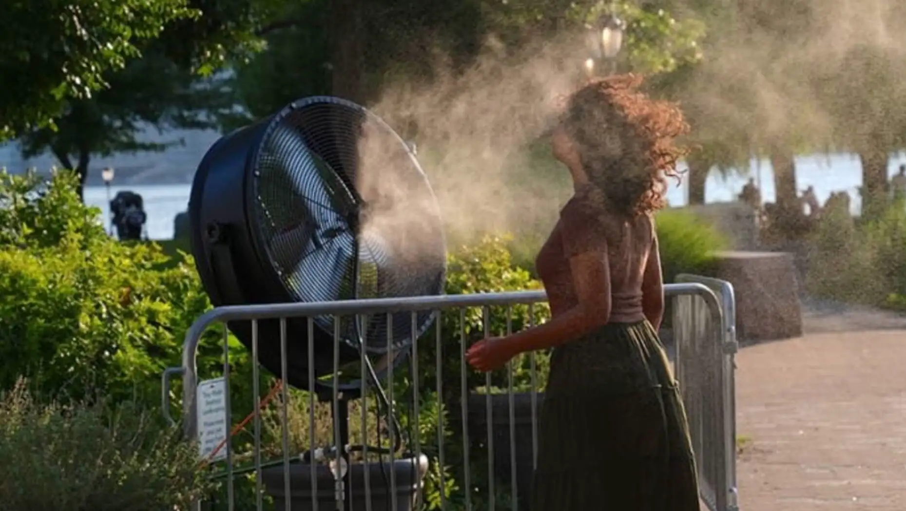 A woman standing next to a fan. A woman standing next to a fan.