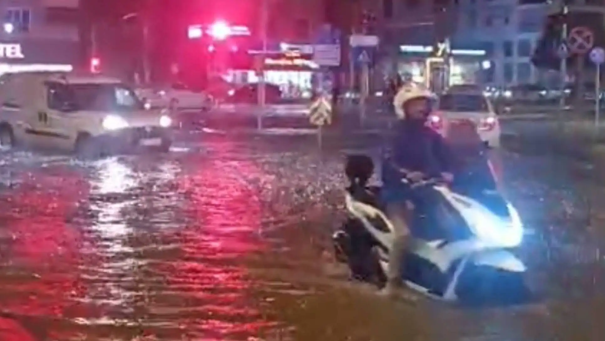 Bir adam, su baskını olan bir sokakta motosiklet sürüyor. Bir adam, su baskını olan bir sokakta motosiklet sürüyor.