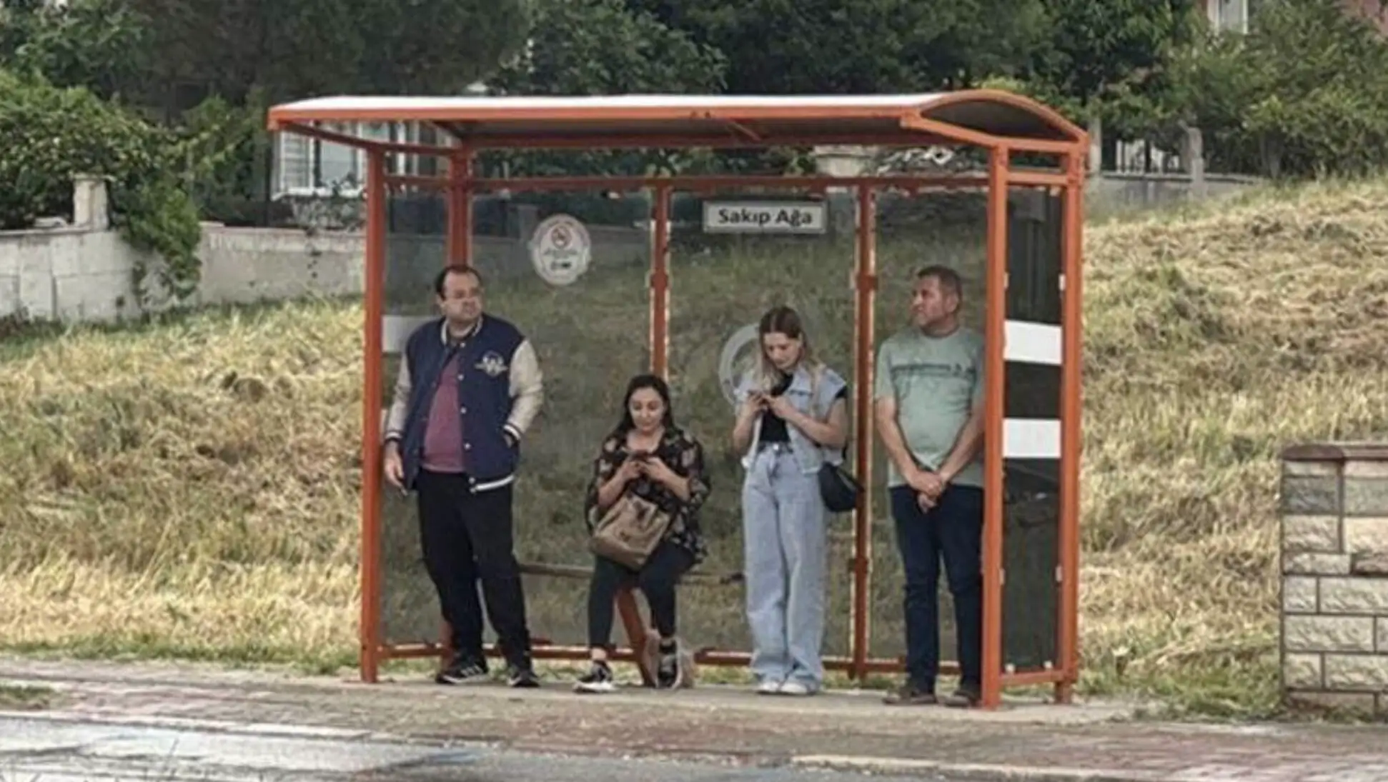 Bir grup insan otobüs durağında bekliyor.