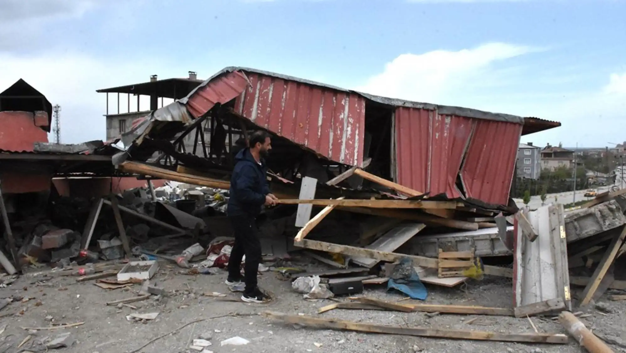 A man standing next to a collapsed building.