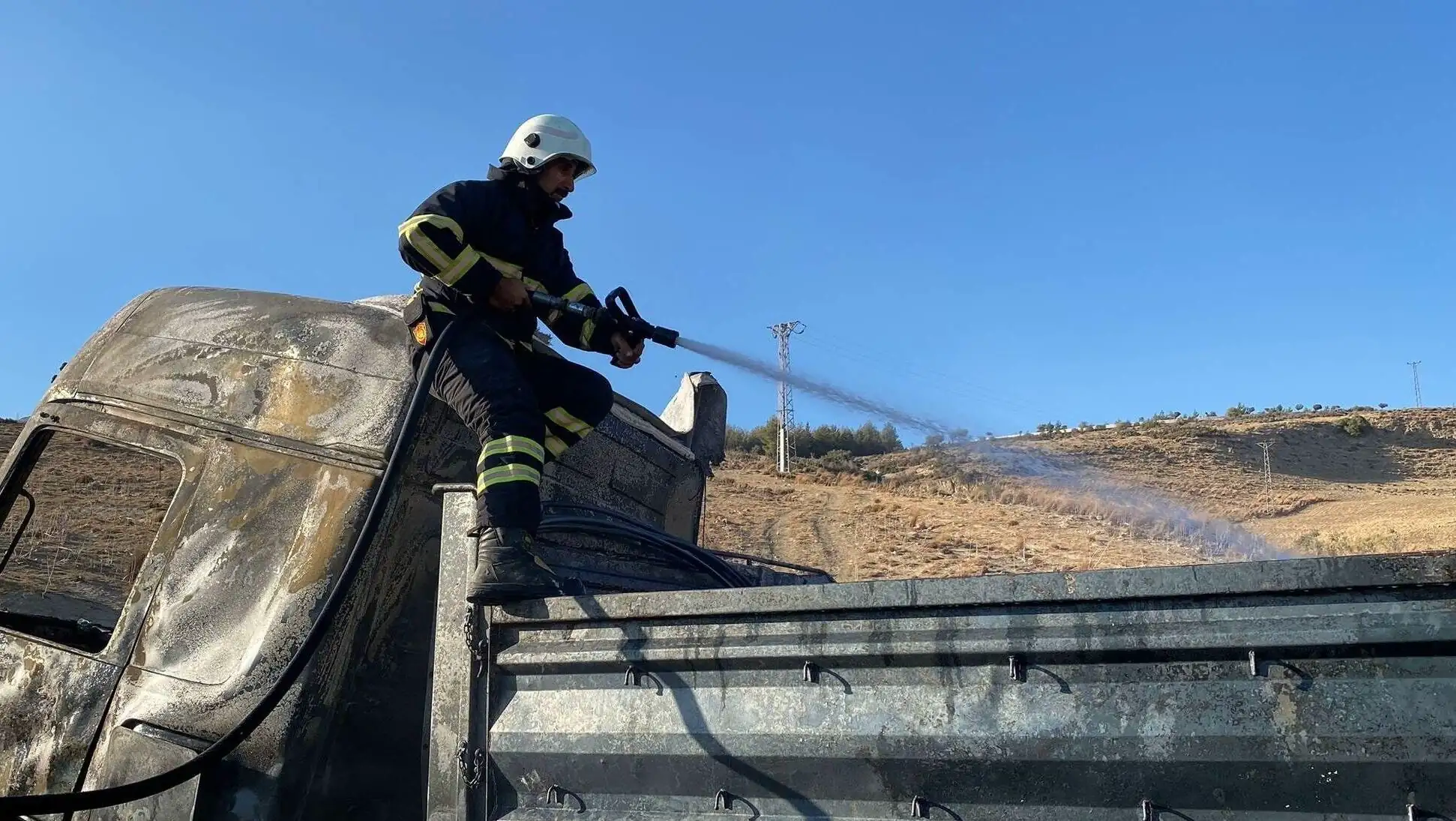 A firefighter spraying water on a truck. A firefighter spraying water on a truck.