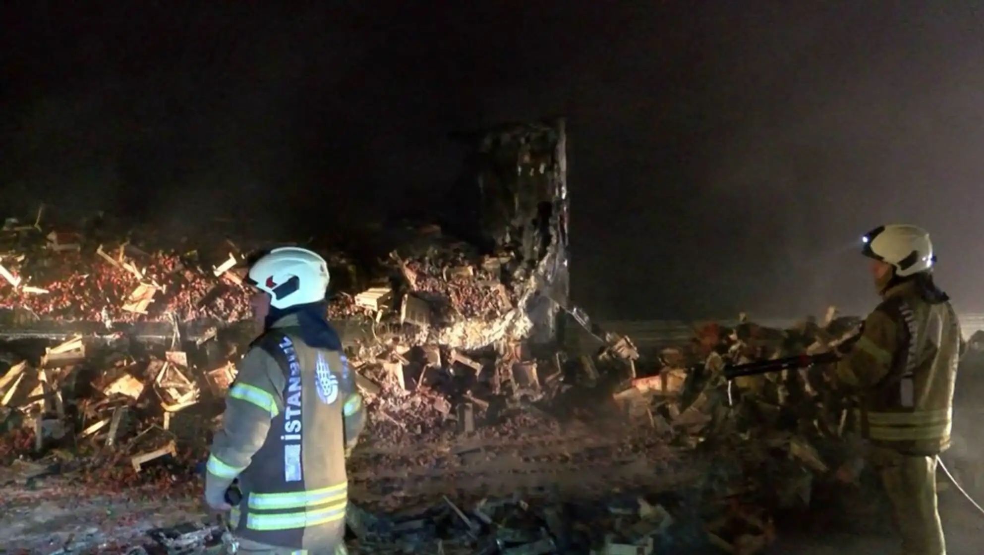 A firefighter standing in front of a destroyed building. A firefighter standing in front of a destroyed building.