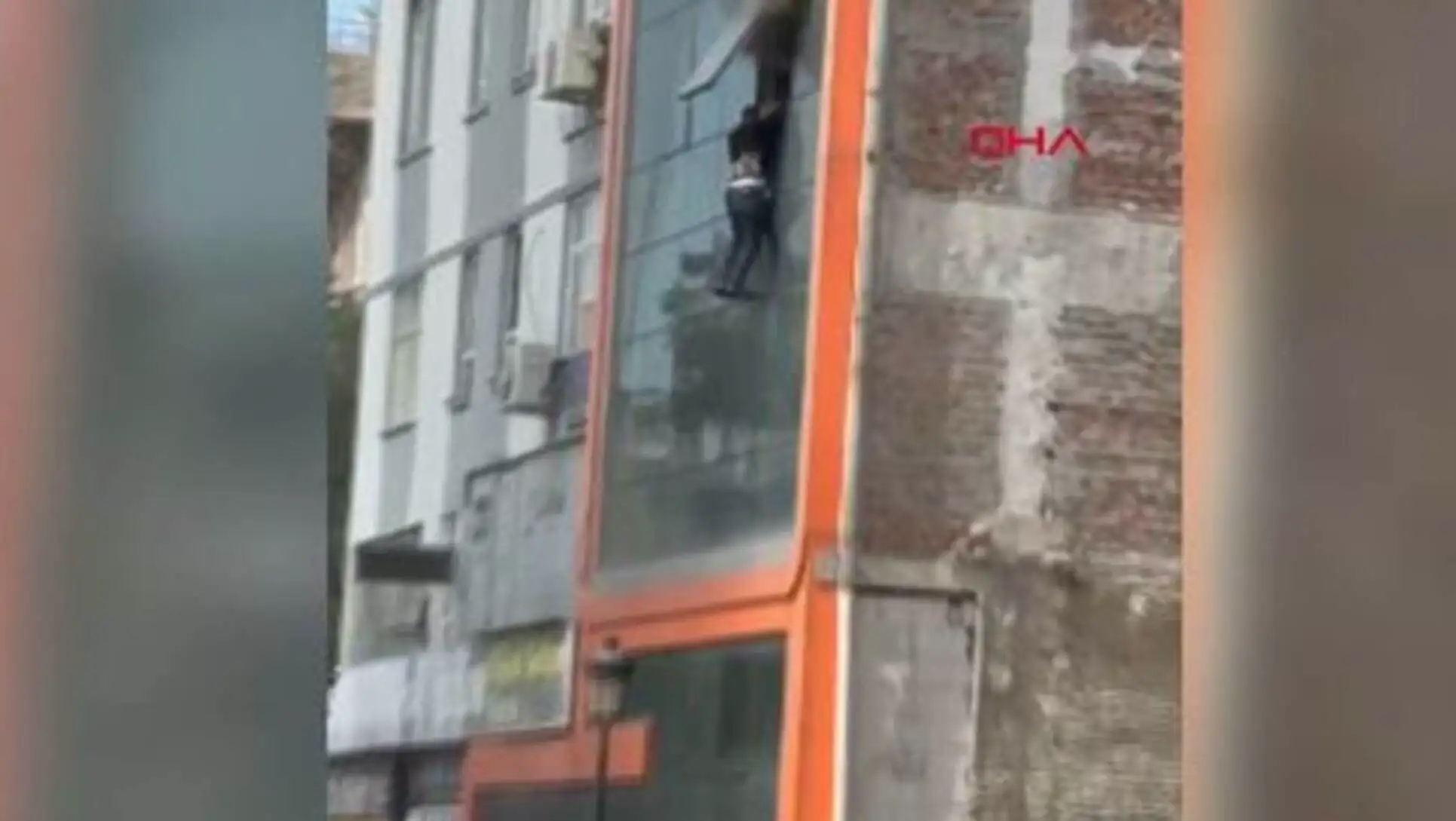Bir işçi pencereden sarkarak kurtulmaya çalışıyor.