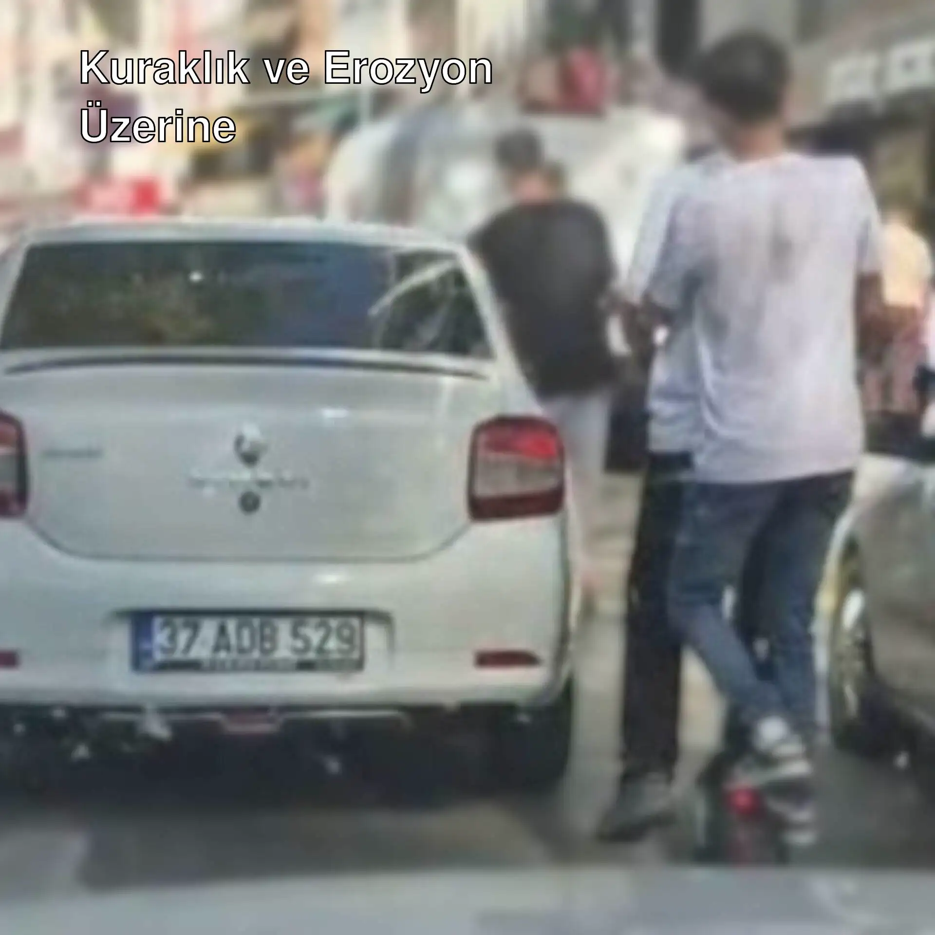 Bir adam beyaz bir arabanın üzerinde duruyor.