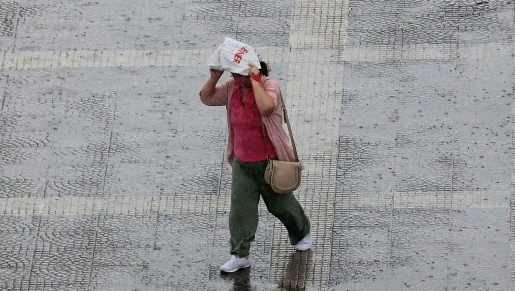 A woman walking on a wet street.
