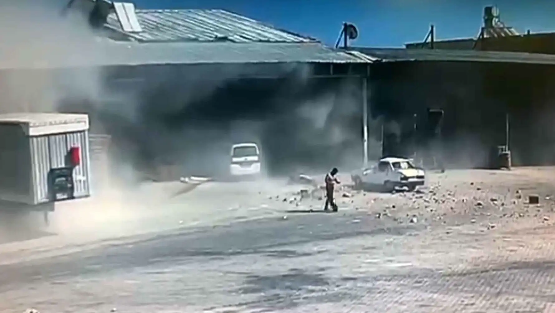 A man standing in front of a building with dust coming out of it.