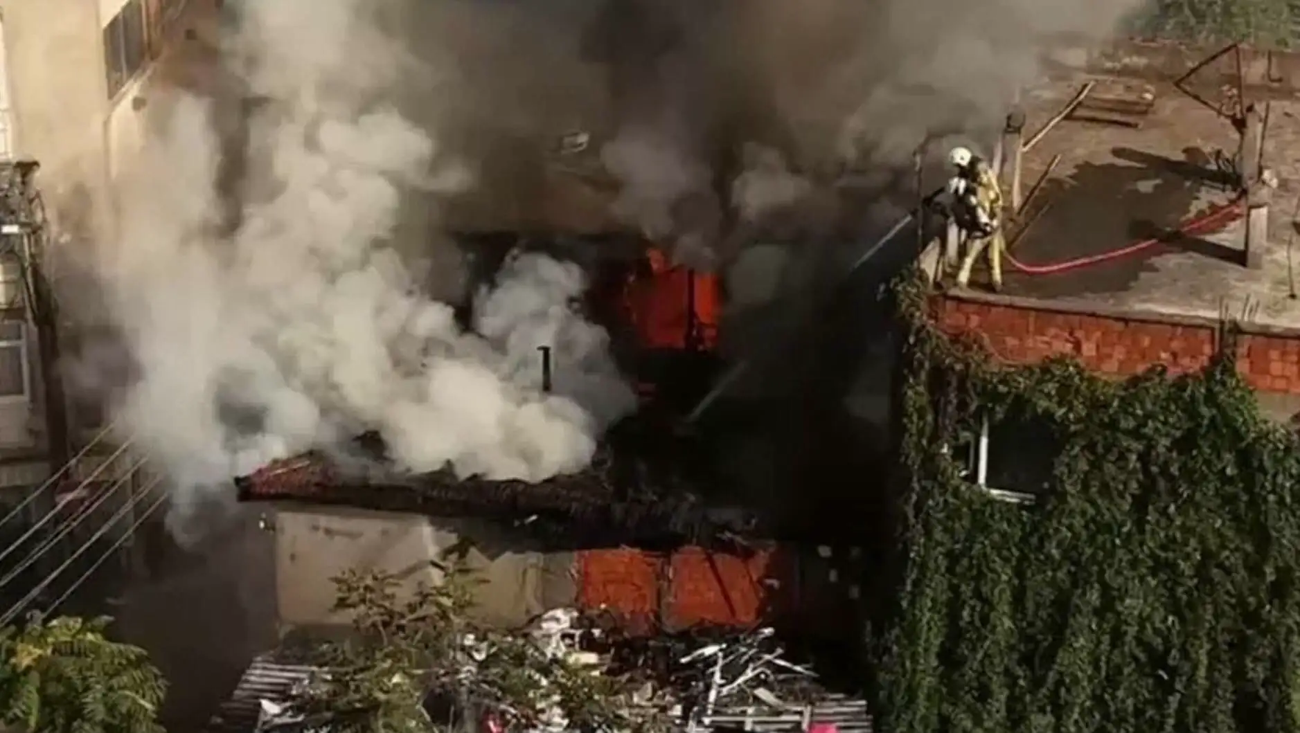 A firefighter on a roof with smoke coming out of it.