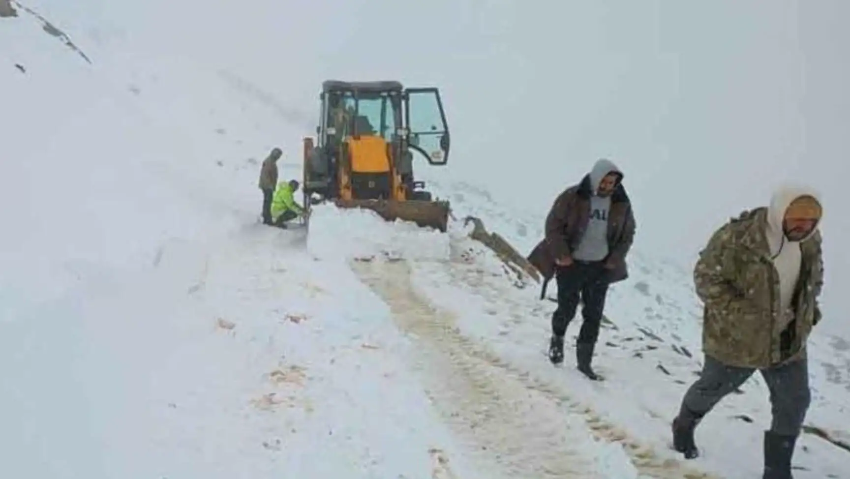 A man standing next to a tractor in the snow.