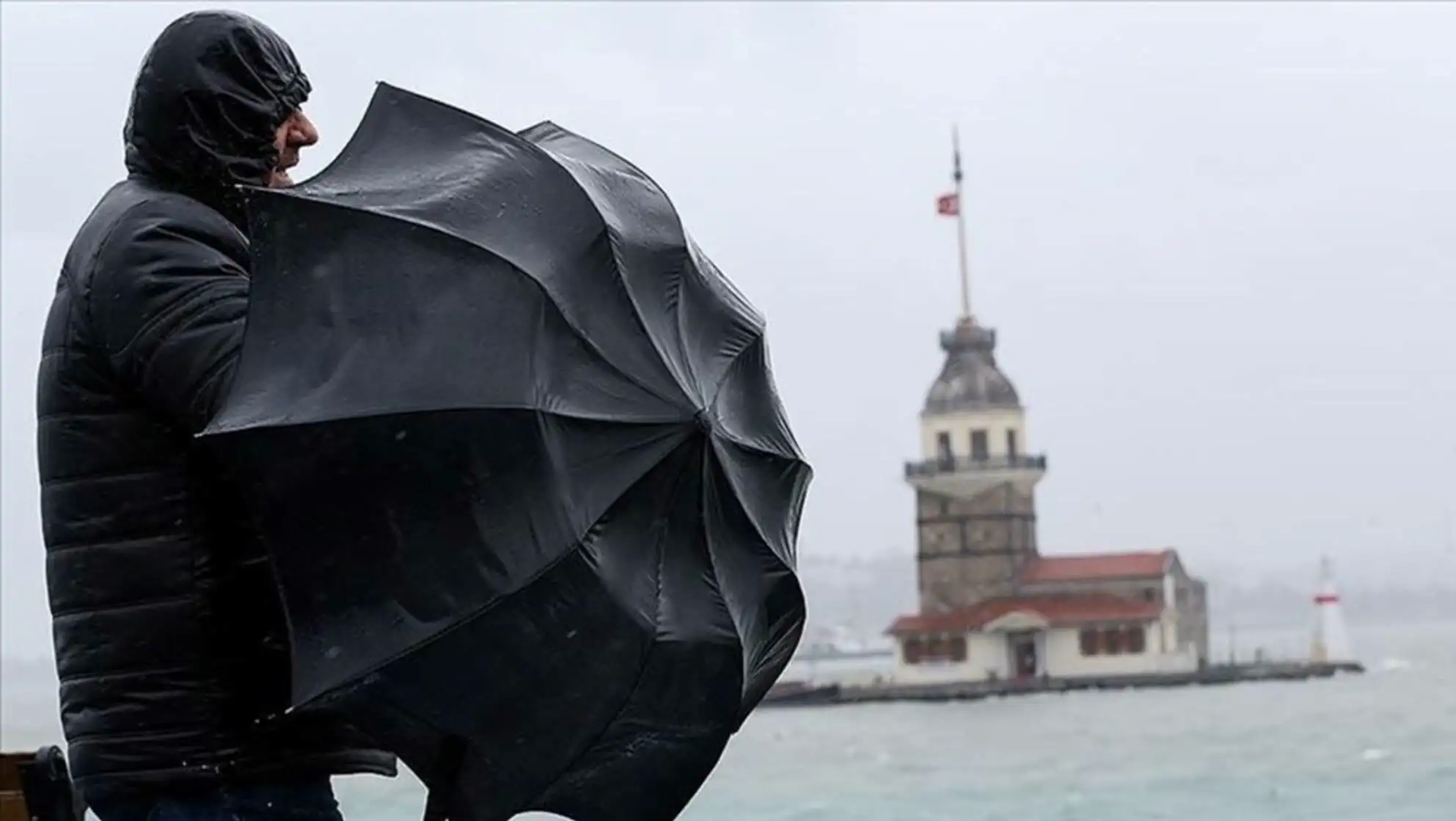 A person holding an umbrella during the storm. Related to weather conditions.