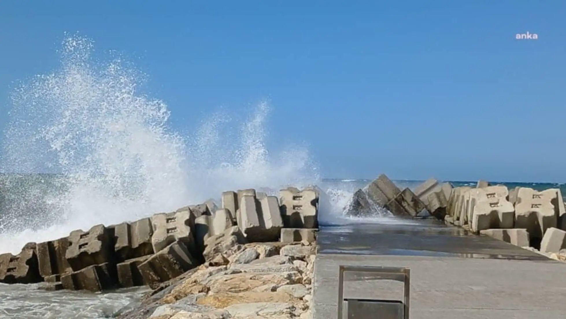 Waves crashing against a concrete wall.