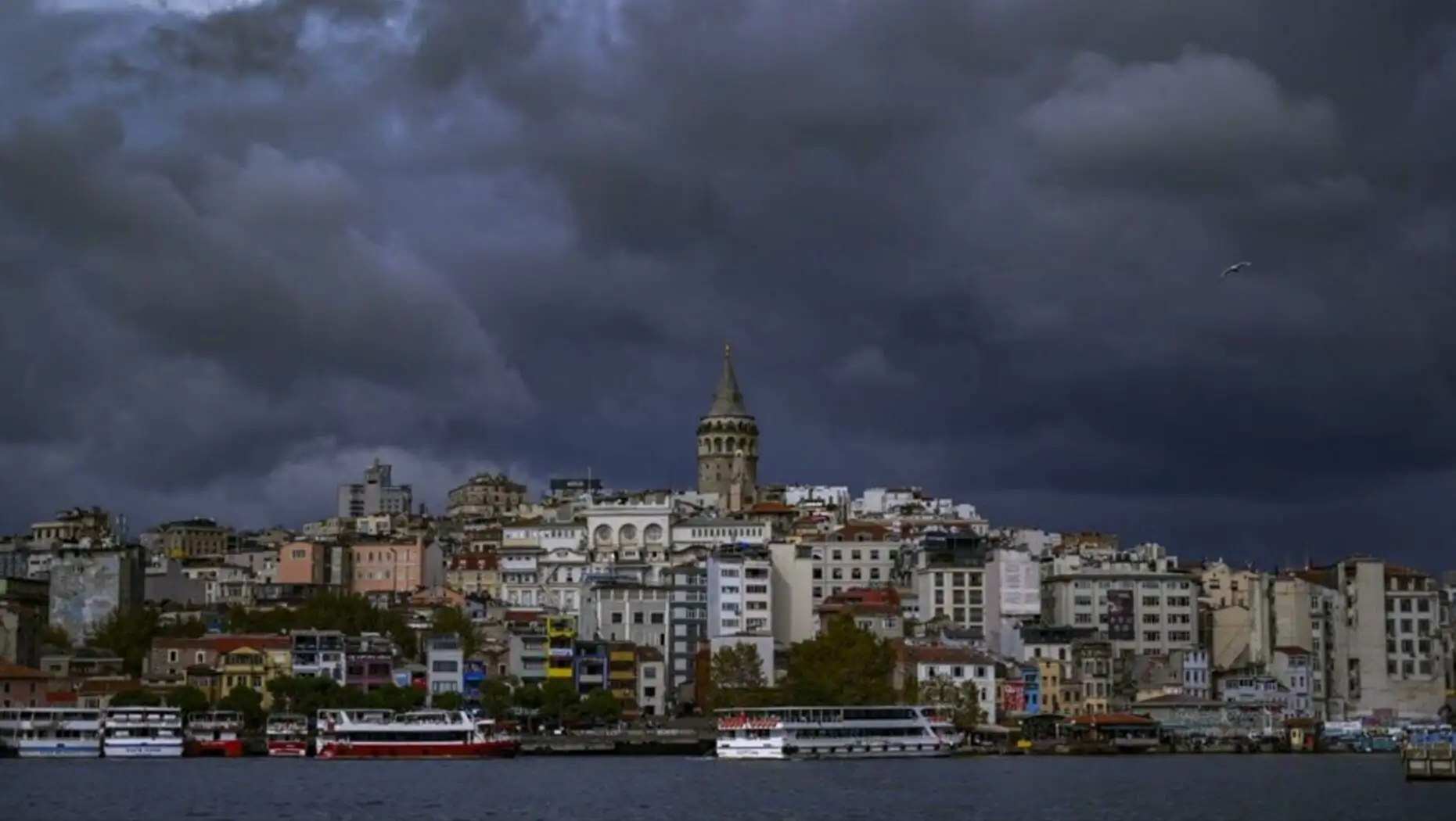 Bir kadın yağmurda yürürken şemsiye tutuyor.