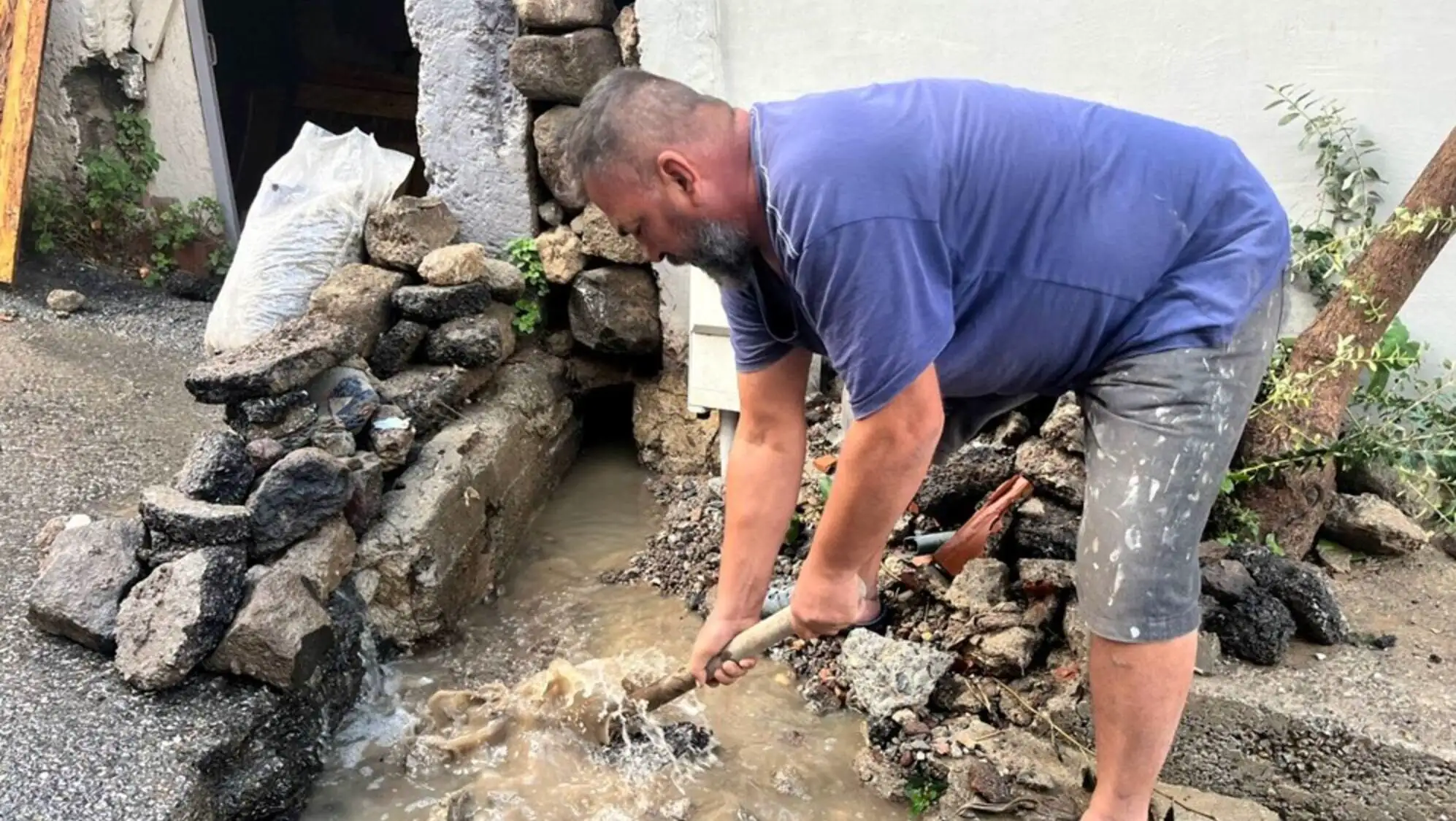 A man holding a stick in a muddy puddle.