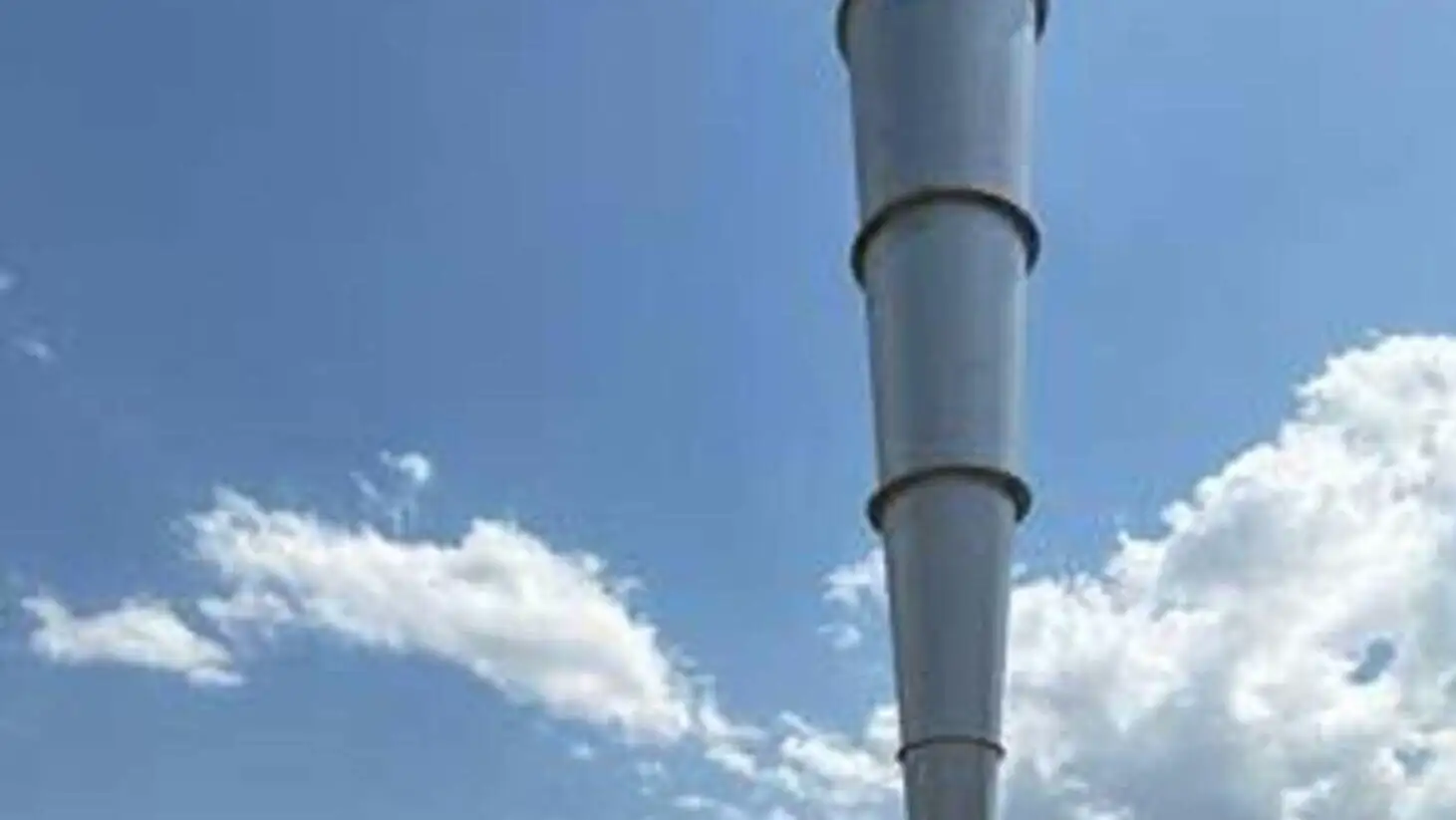 Bir adam yüksek metal bir kule yanında duruyor.