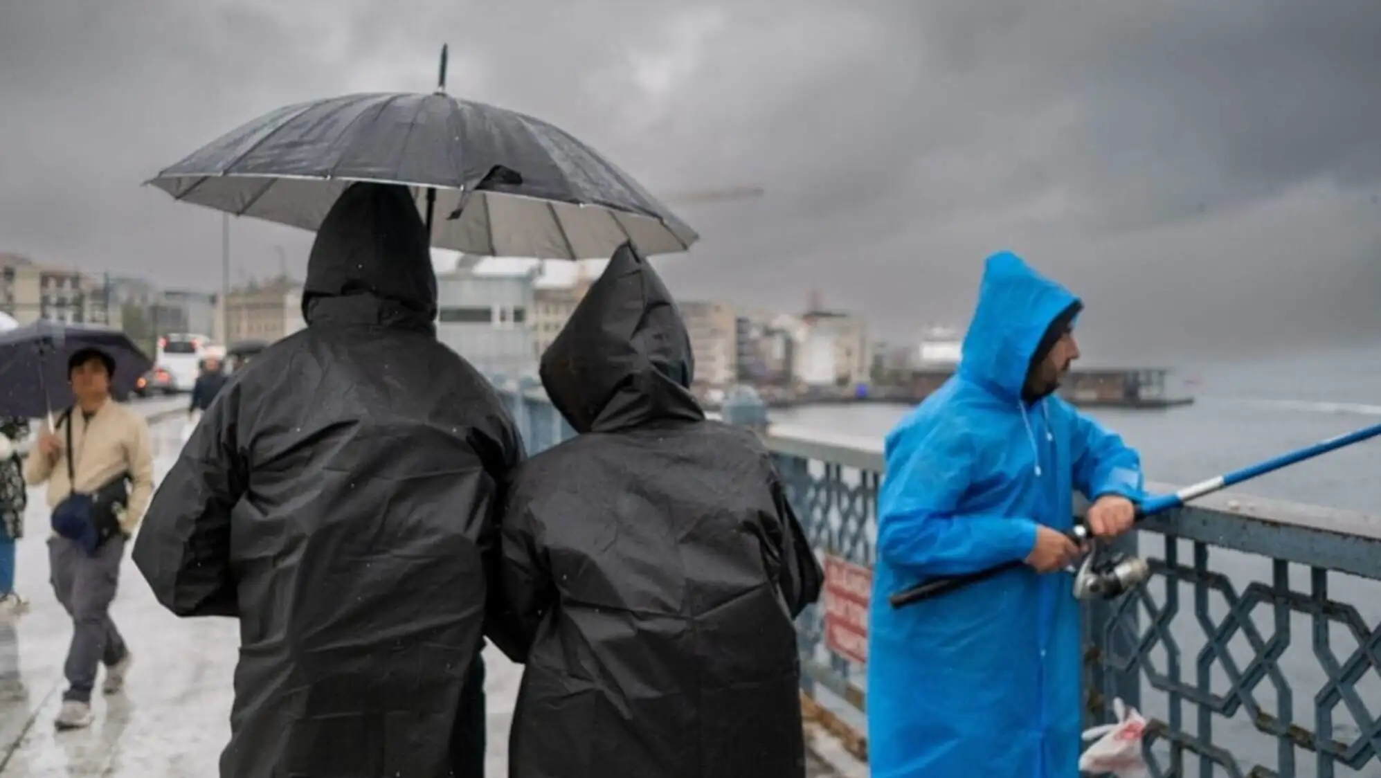A group of people wearing raincoats standing on a bridge. A group of people wearing raincoats standing on a bridge.
