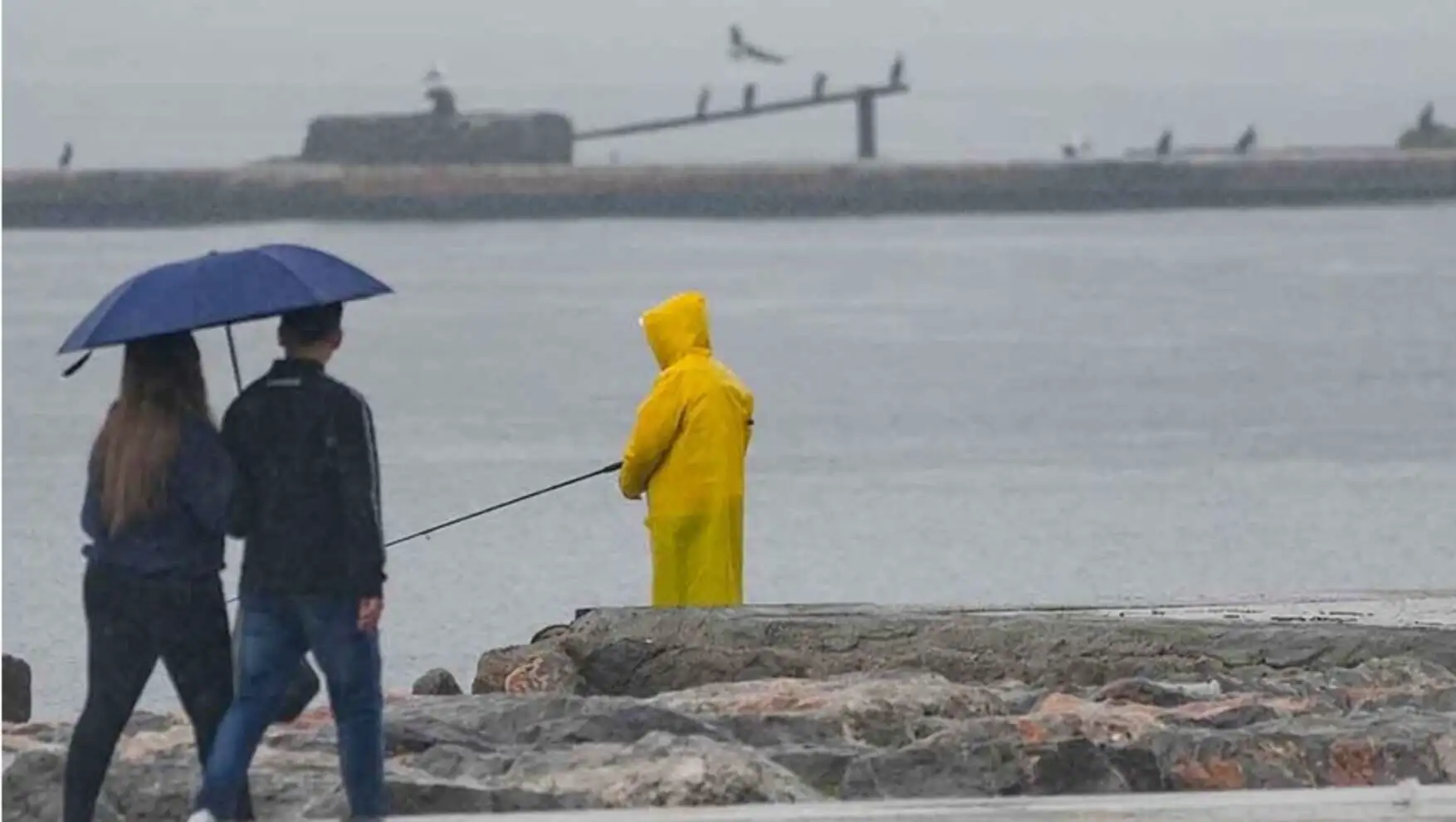 A person holding a fishing pole in a raincoat. A person holding a fishing pole in a raincoat.
