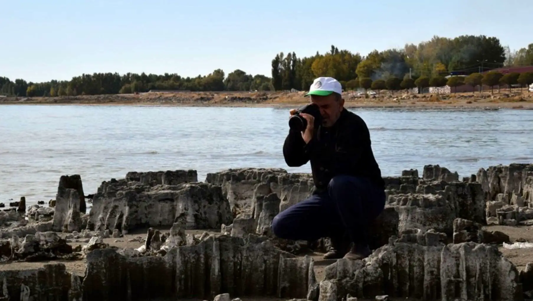 A man taking a picture of a rocky beach. A man taking a picture of a rocky beach.