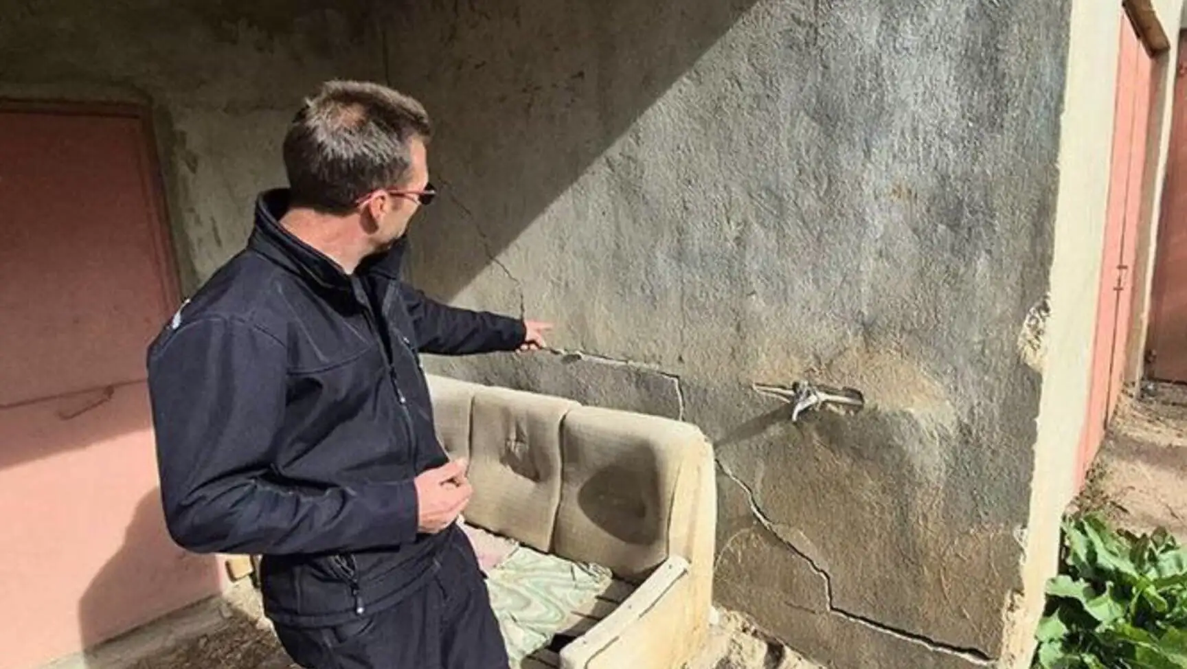 A man pointing to a crack in the wall in Eğirdir.