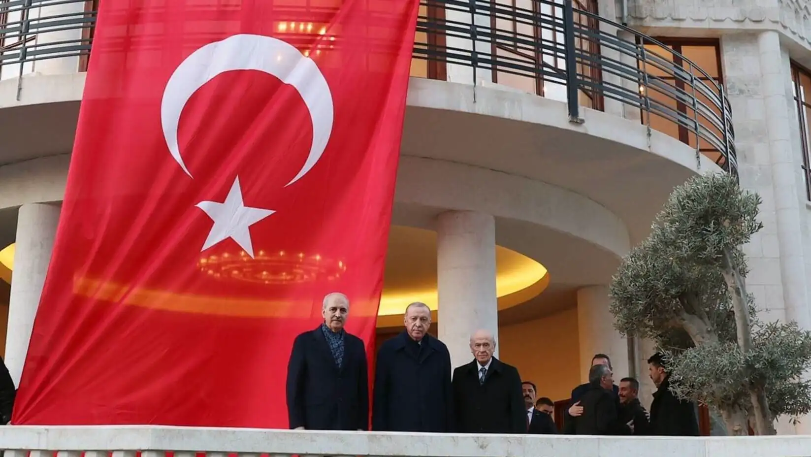 A group of men standing in front of a building with a flag. A group of men standing in front of a building with a flag.