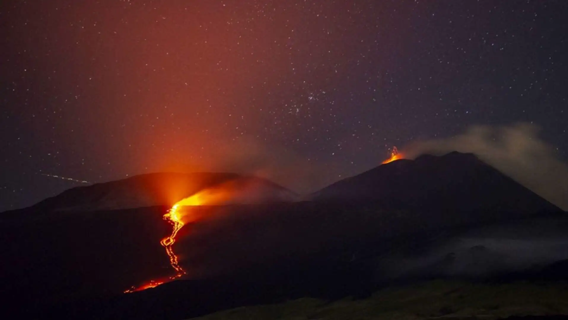 A mountain with lava flowing down the top.