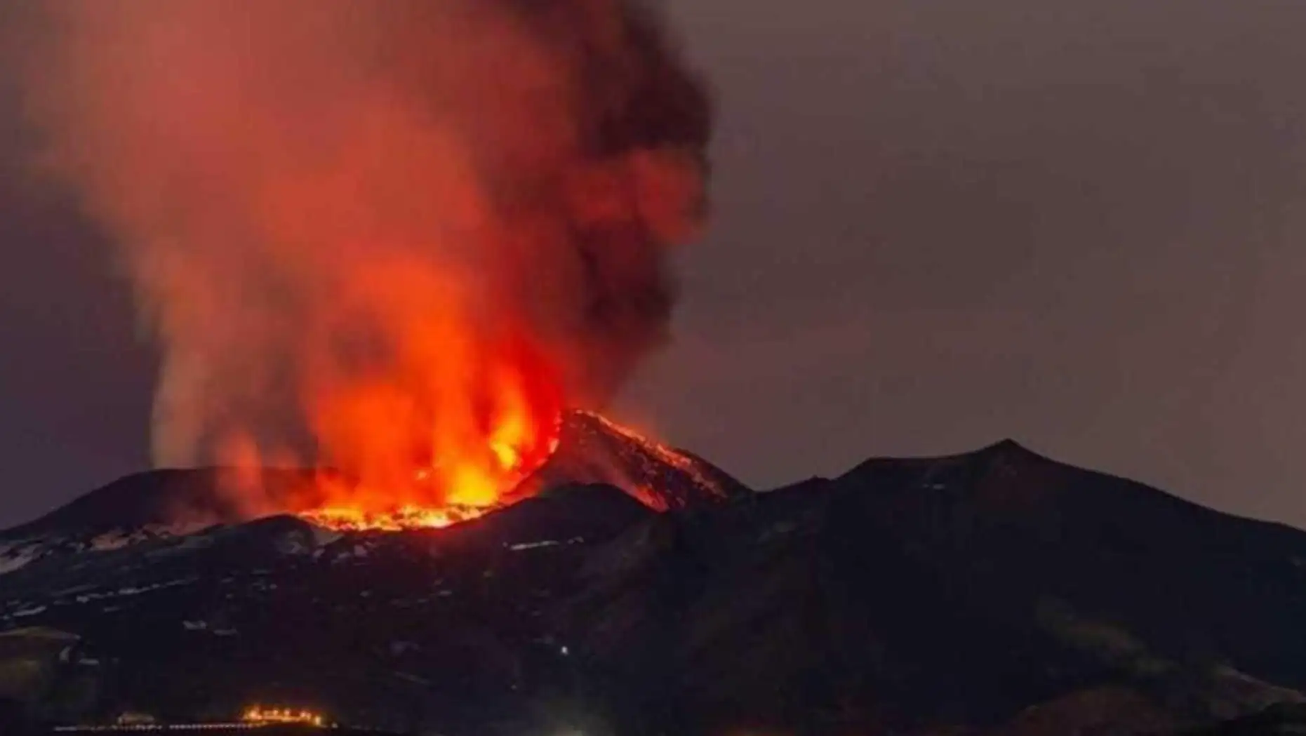 A mountain with fire and smoke from a volcano.