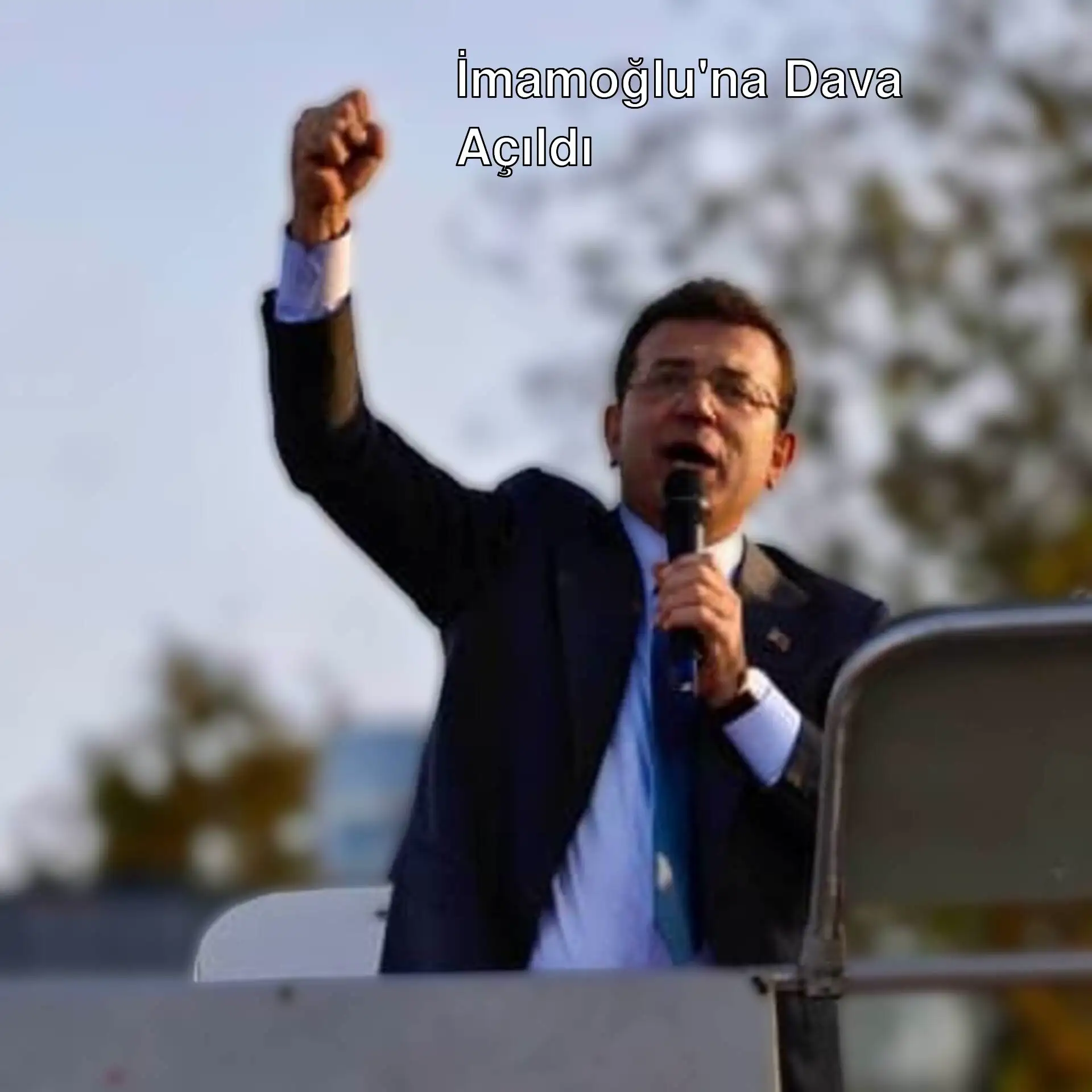 Ekrem İmamoğlu mikrofon tutuyor ve elini kaldırıyor. Ekrem İmamoğlu mikrofon tutuyor ve elini kaldırıyor.