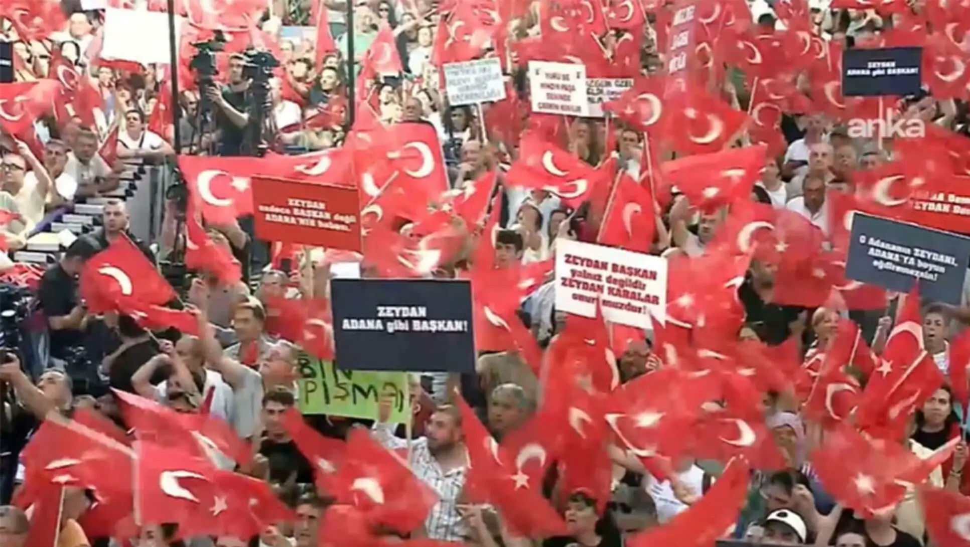Kalabalık bir grup, mitingde bayraklar tutuyor. Kalabalık bir grup, mitingde bayraklar tutuyor.