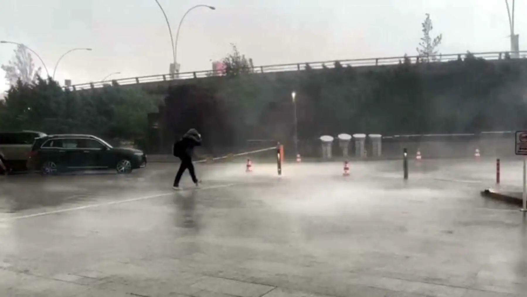 Bir kişi su birikintisi olan bir otoparkta yürüyor. Bir kişi su birikintisi olan bir otoparkta yürüyor.