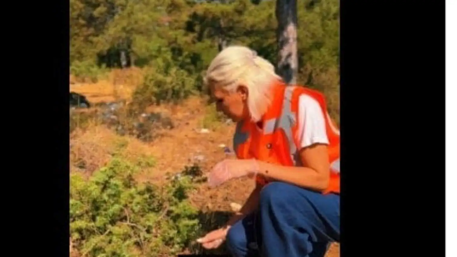 A woman kneeling in the dirt during a cleaning event.