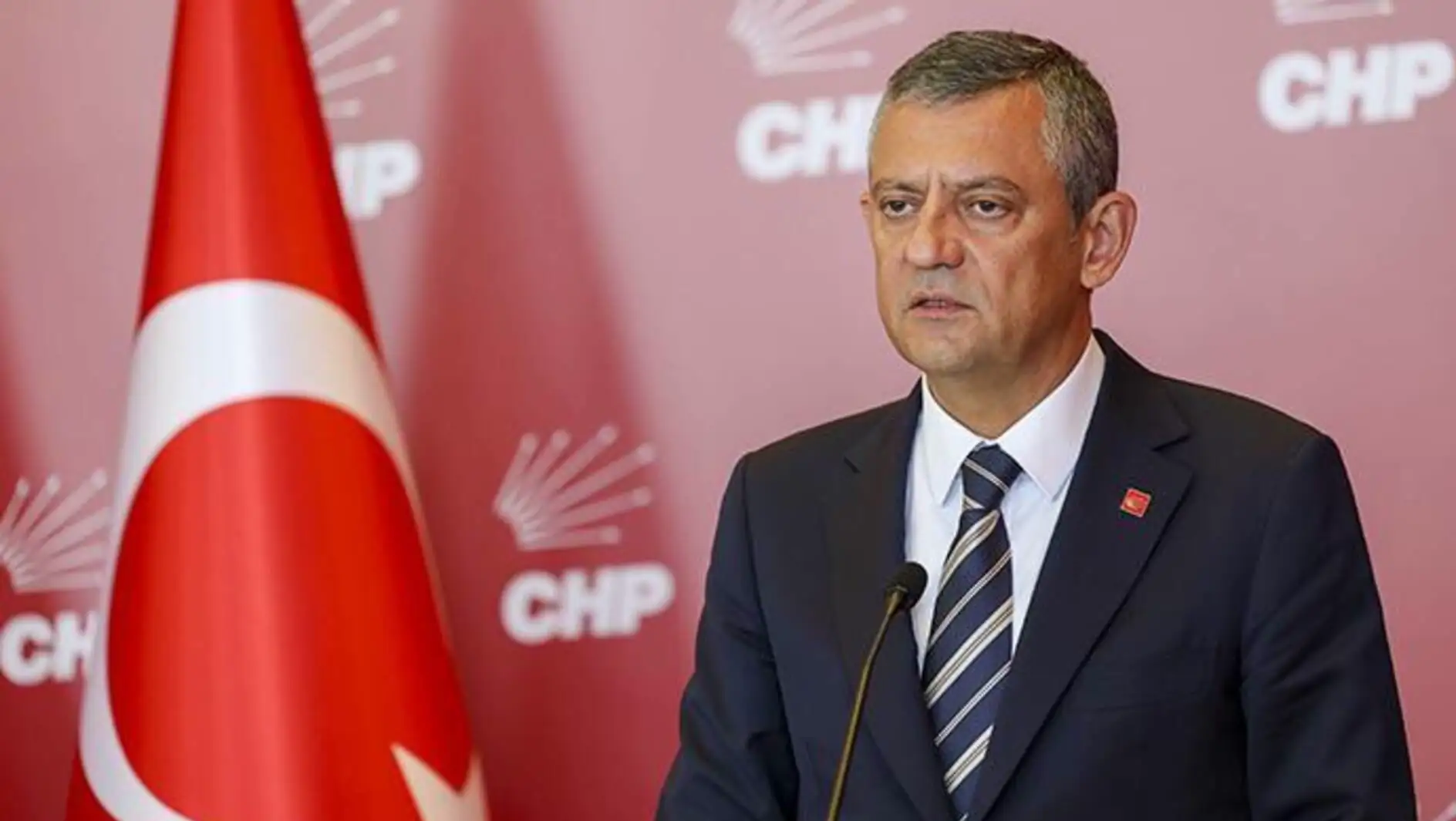 Bir adam takım elbise giymiş, bayrak önünde duruyor. Bir adam takım elbise giymiş, bayrak önünde duruyor.