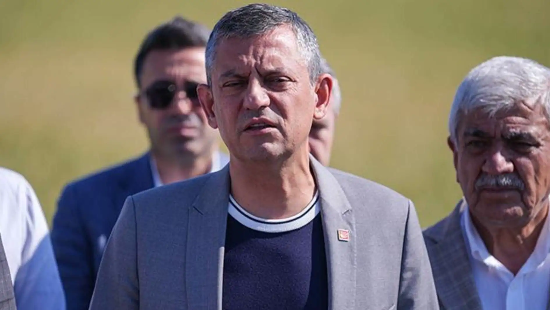 Özgür Özel holding a microphone at a press conference.