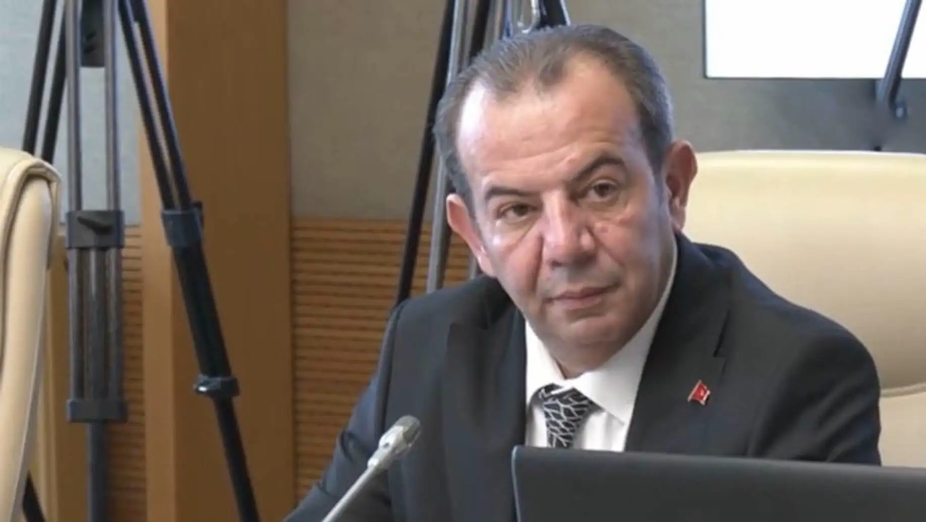 A man in a suit sitting at a microphone.