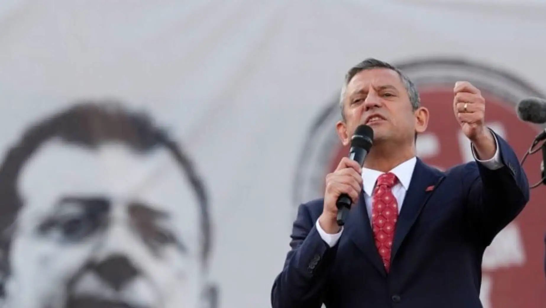 Özgür Özel holding a microphone while speaking.