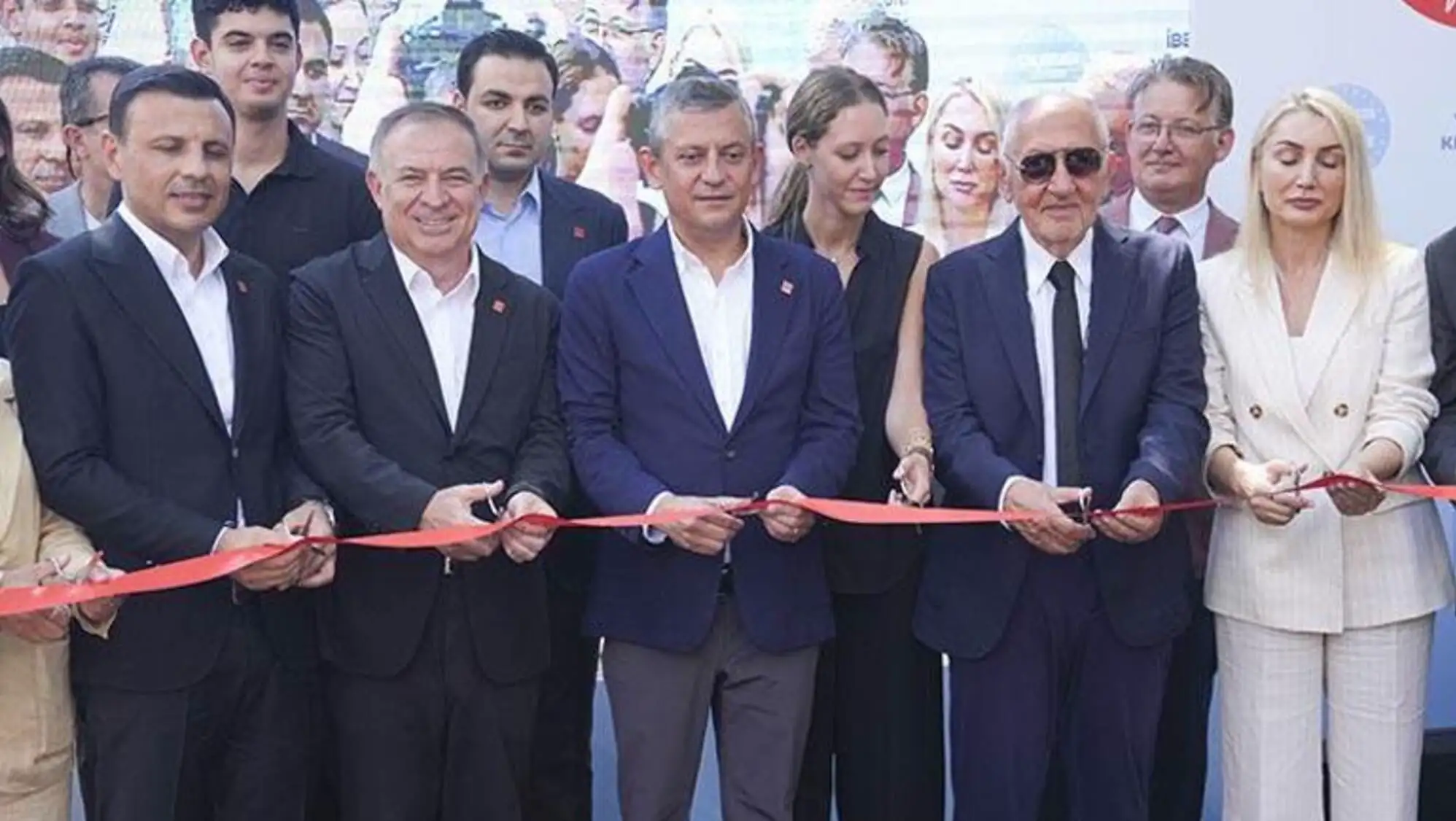 A group of people cutting a red ribbon. A group of people cutting a red ribbon.