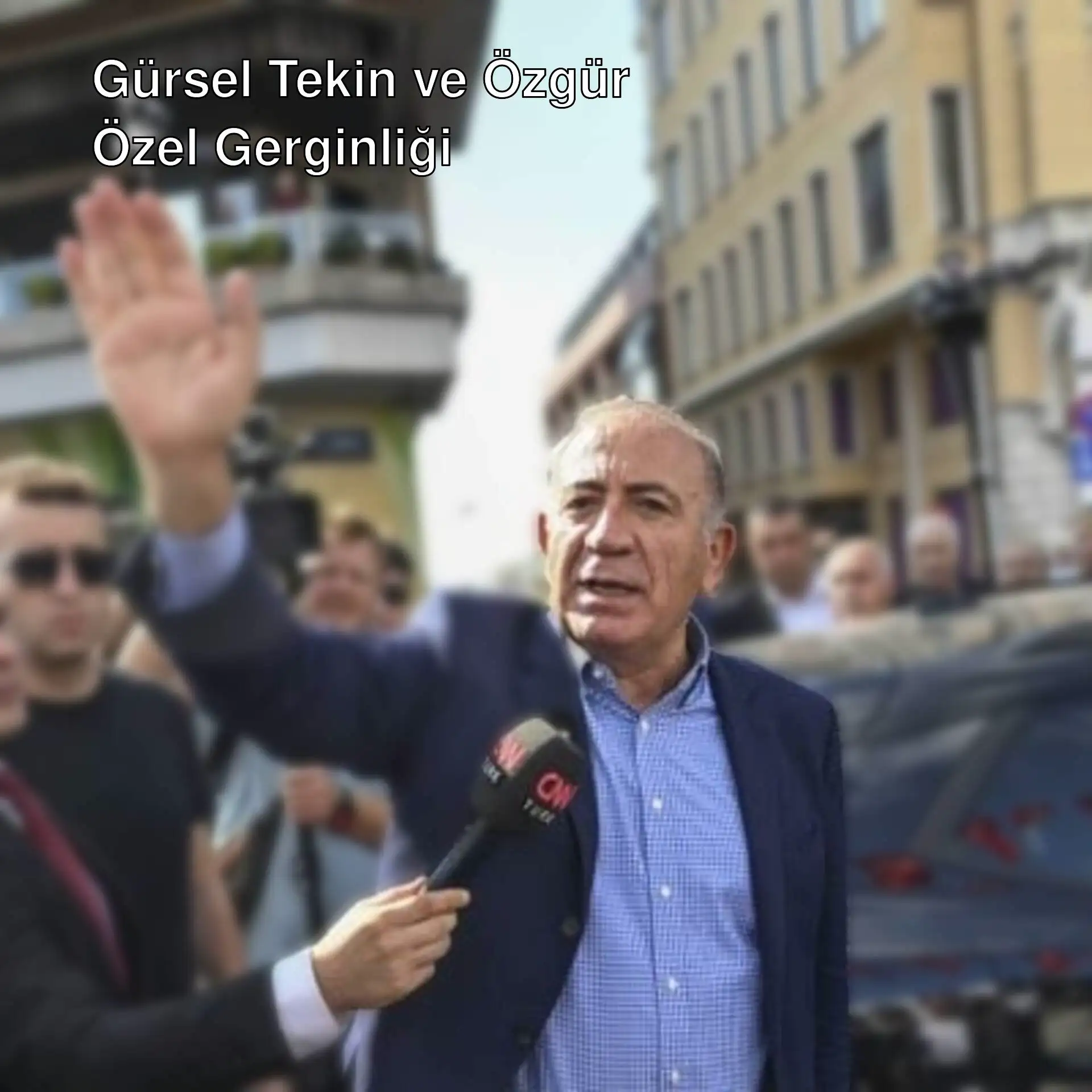 Gürsel Tekin bir grup insana mikrofonla konuşuyor.