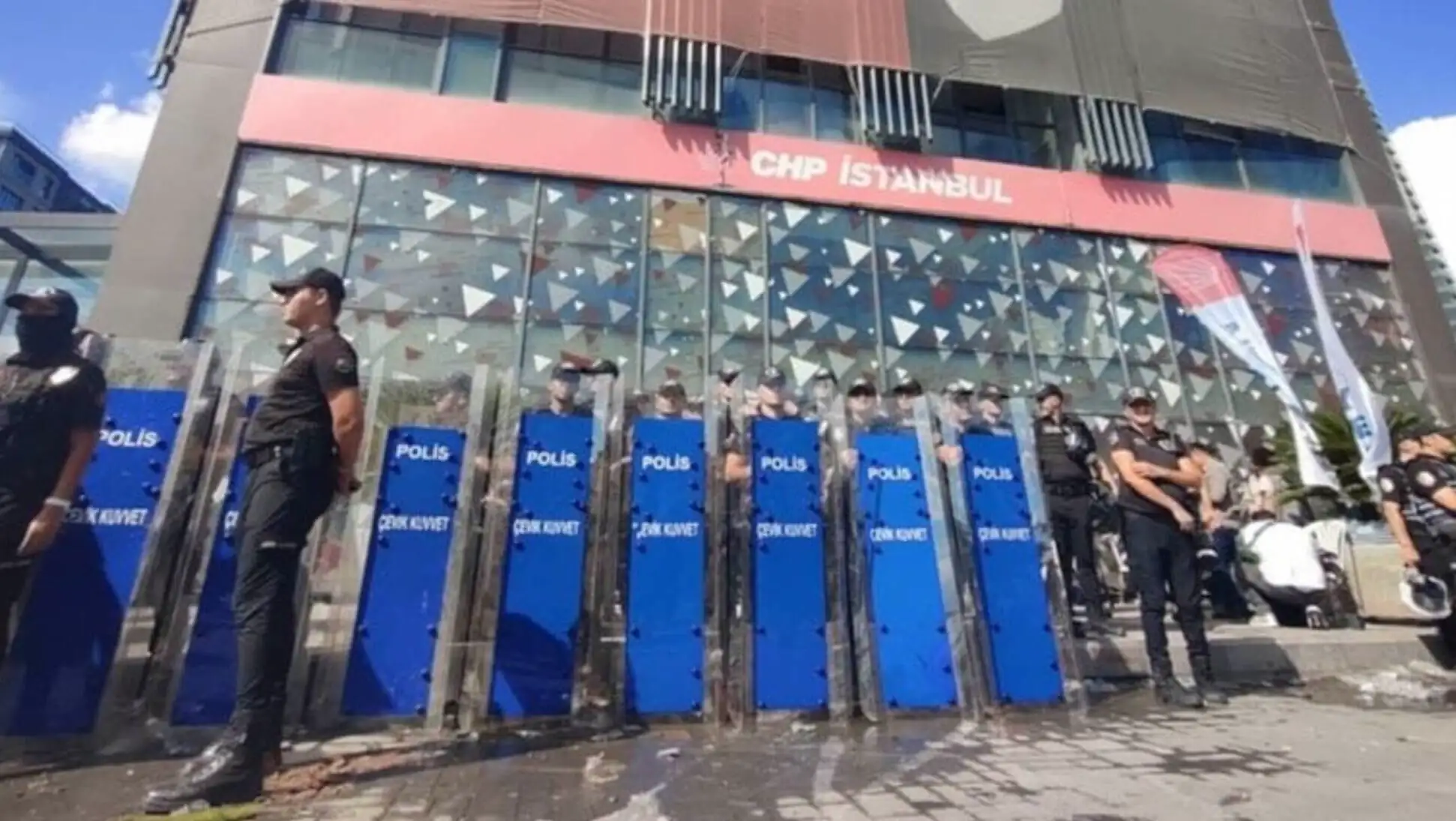 Bir grup insan bir binanın önünde duruyor.