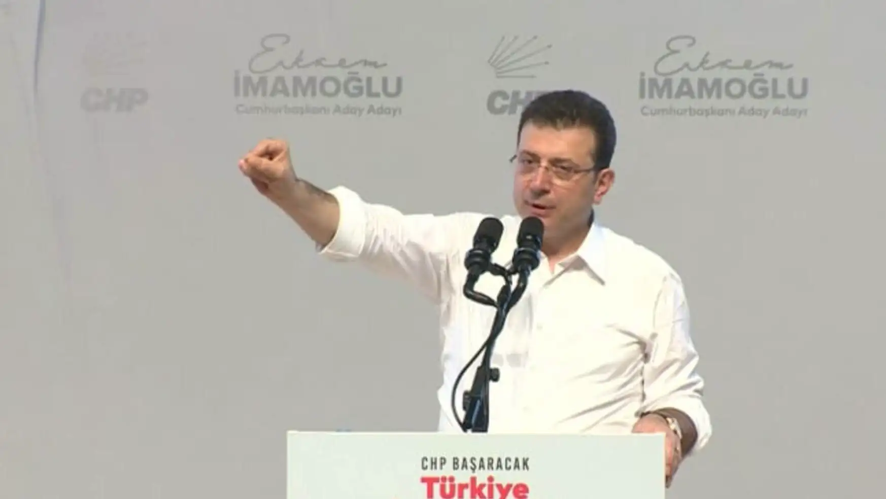 Imamoğlu raising his hand in front of a microphone.