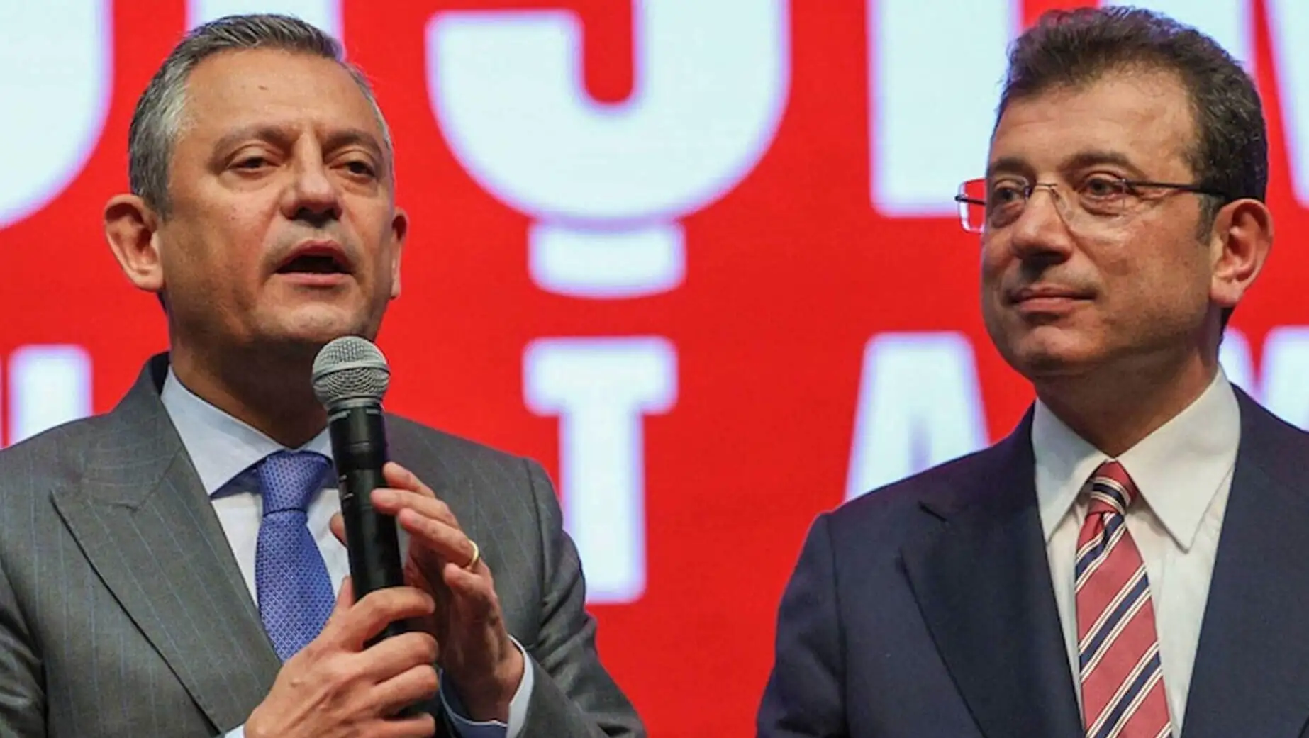 Two men in suits holding a microphone.