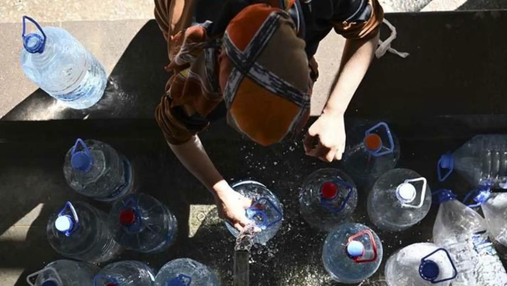 A person filling water bottles.