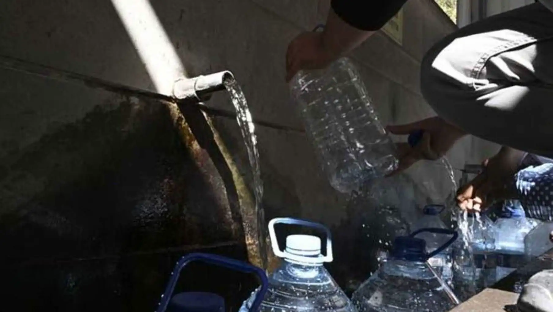 A person pouring water into a faucet.
