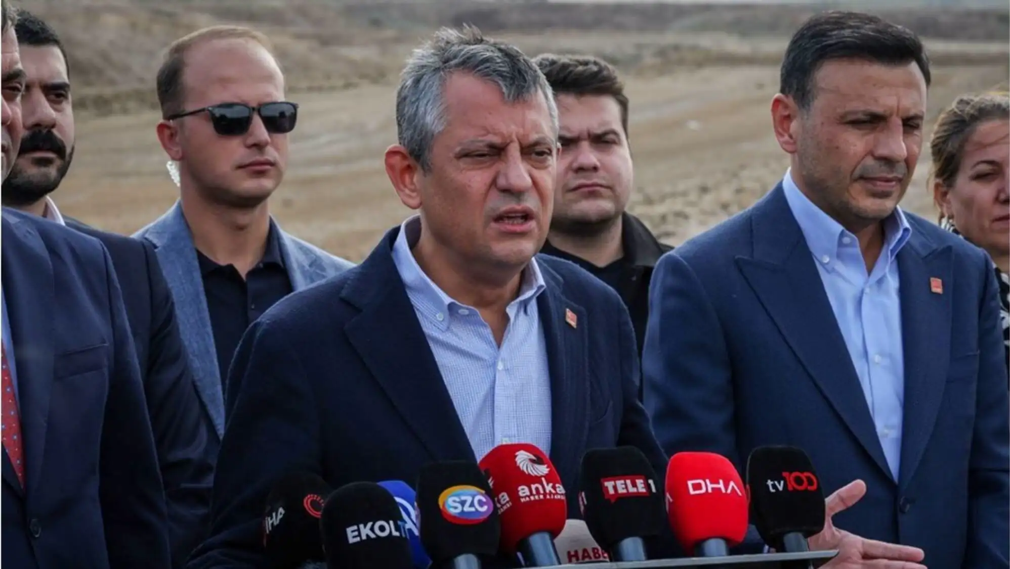 Bir grup adam mikrofonların önünde duruyor.