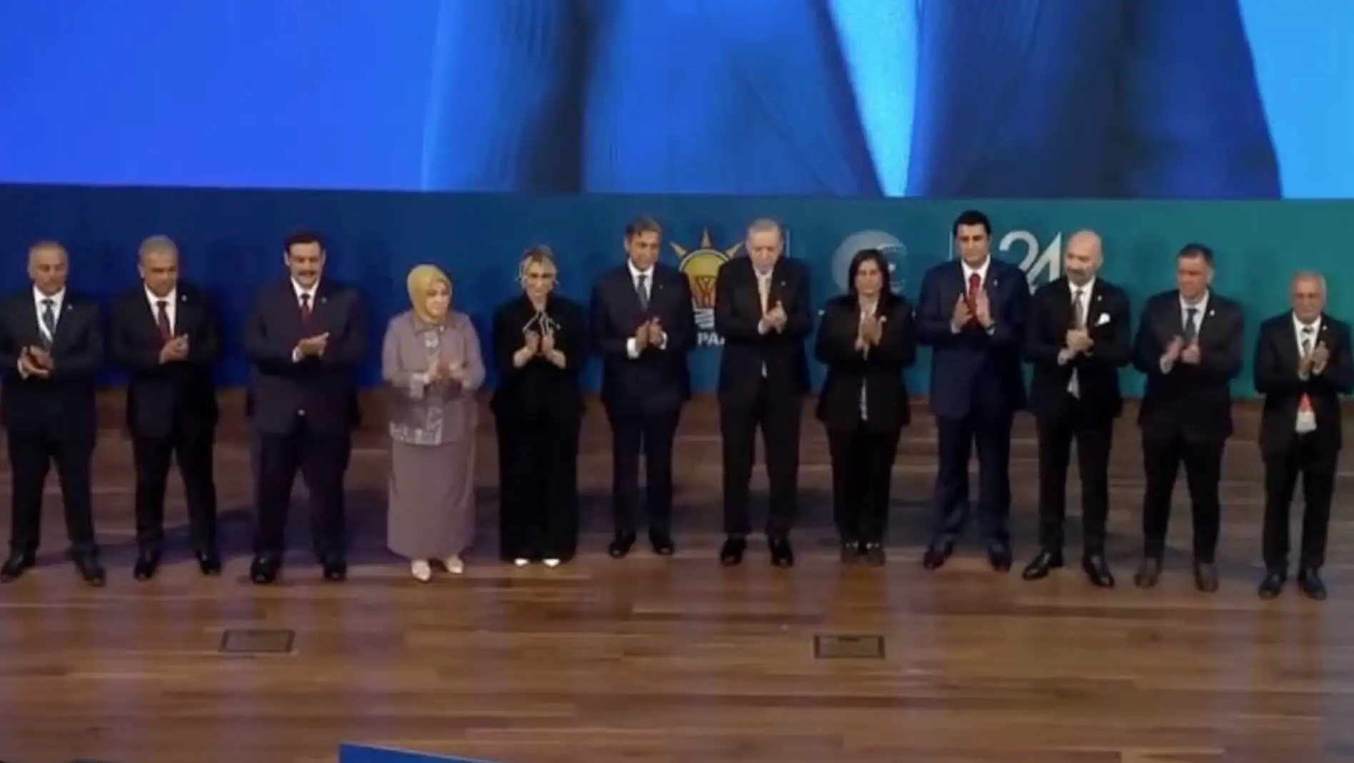 Bir grup insan ahşap zemin üzerinde duruyor.