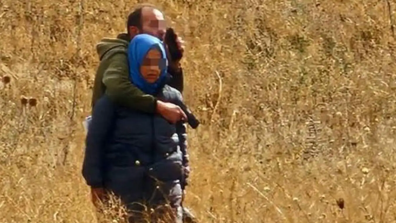 A man carrying a child in a field. A man carrying a child in a field.